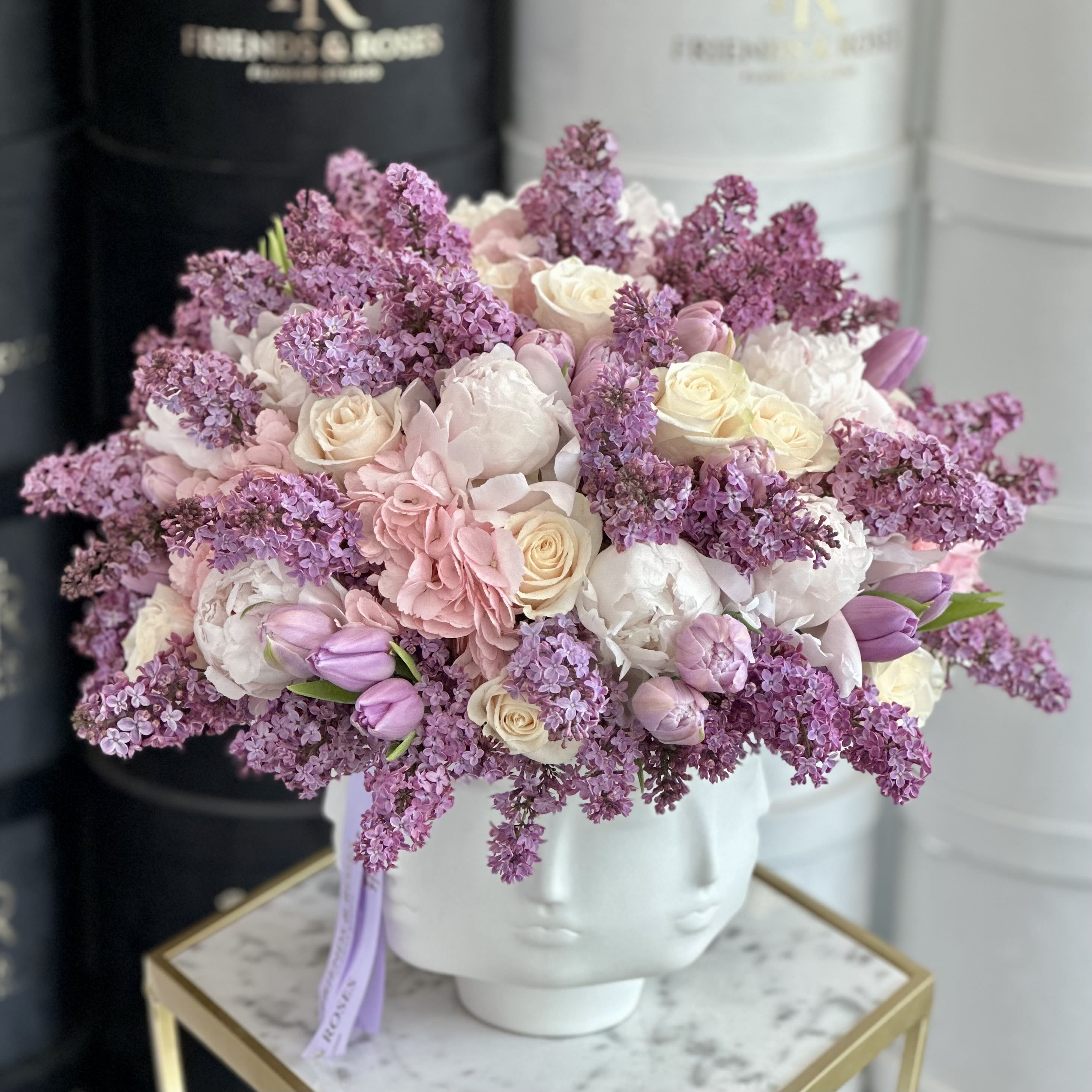 Dream  (Jonathan Adler Collection) - A charming floral composition featuring lilacs, tulips, peonies, and roses, artfully gathered in an unusual and eye-catching vase from the Jonathan Adler collection. The blend of delicate petals and bold design creates a striking contrast-romantic, whimsical, and undeniably elegant. Perfect as a statement piece, this arrangement brings a touch of modern sophistication to any space.  Dora Maar Bowl can be purchased separate for $ 325    
