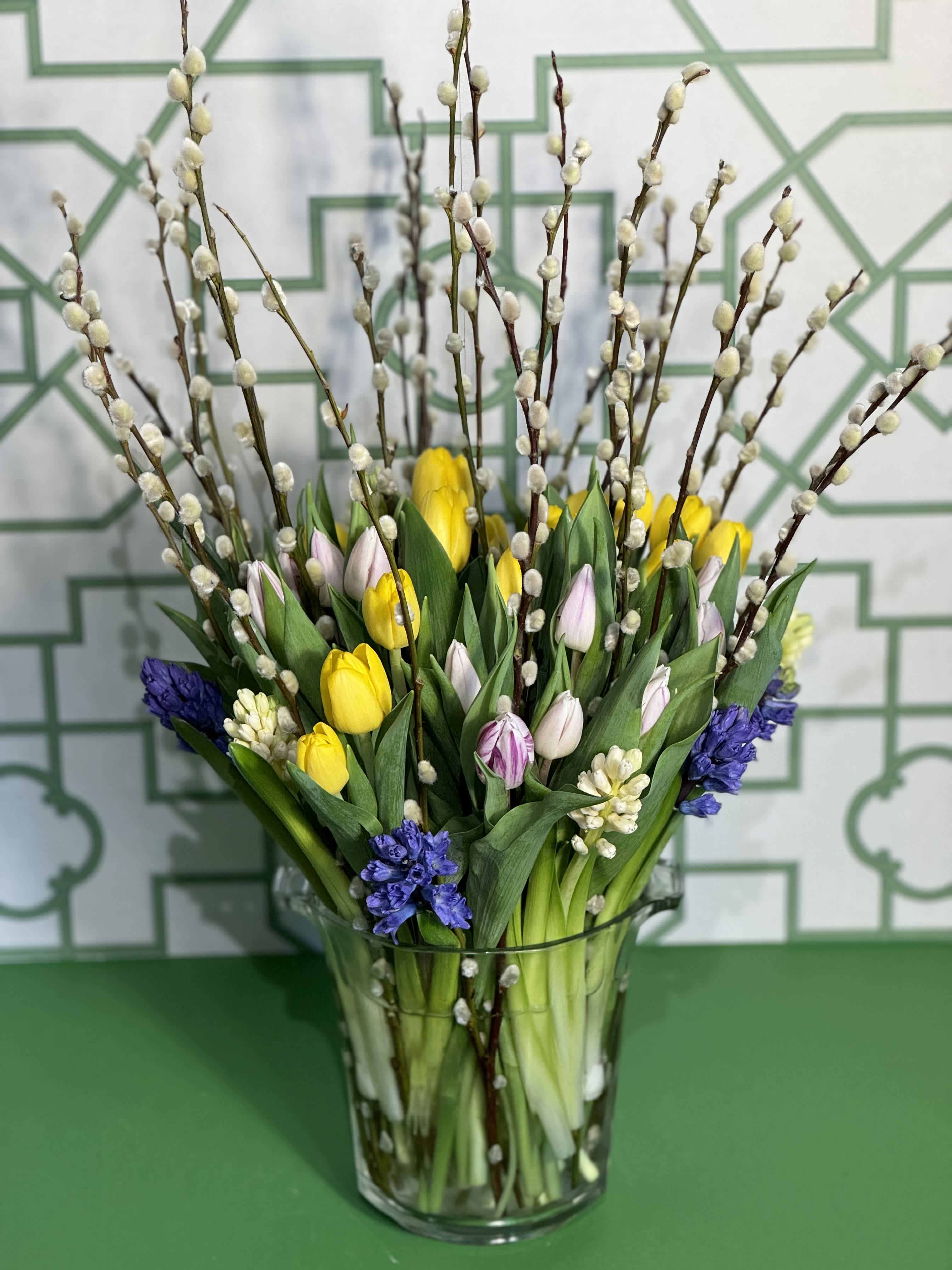 Spring Harmony - Embrace the lively spirit of spring with Spring Harmony, an enchanting floral arrangement from our exclusive Spring Collection. This vibrant display features a delightful blend of fresh tulips, fragrant hyacinths, and whimsical pussy willow, all beautifully arranged in a stylish gathering vase. The perfect way to add a burst of color and joy to any occasion, Spring Harmony captures the essence of the season.  Please note: The color of flowers may vary depending on seasonal availability, ensuring each arrangement is unique.  At Belden's Florist we stand behind the quality of our products. We guarantee that our flowers will remain fresh and beautiful for 3-5 days after delivery. As cut flowers, they may naturally start to wilt beyond this timeframe. However, we ensure that you receive the freshest blooms possible, carefully selected and expertly arranged to bring joy and elegance to your space. To help your flowers stay fresher longer, we recommend adding fresh water to the vase regularly. Just like you, flowers need hydration to thrive, and refreshing the water allows them to drink up and continue to dazzle you with their beauty.