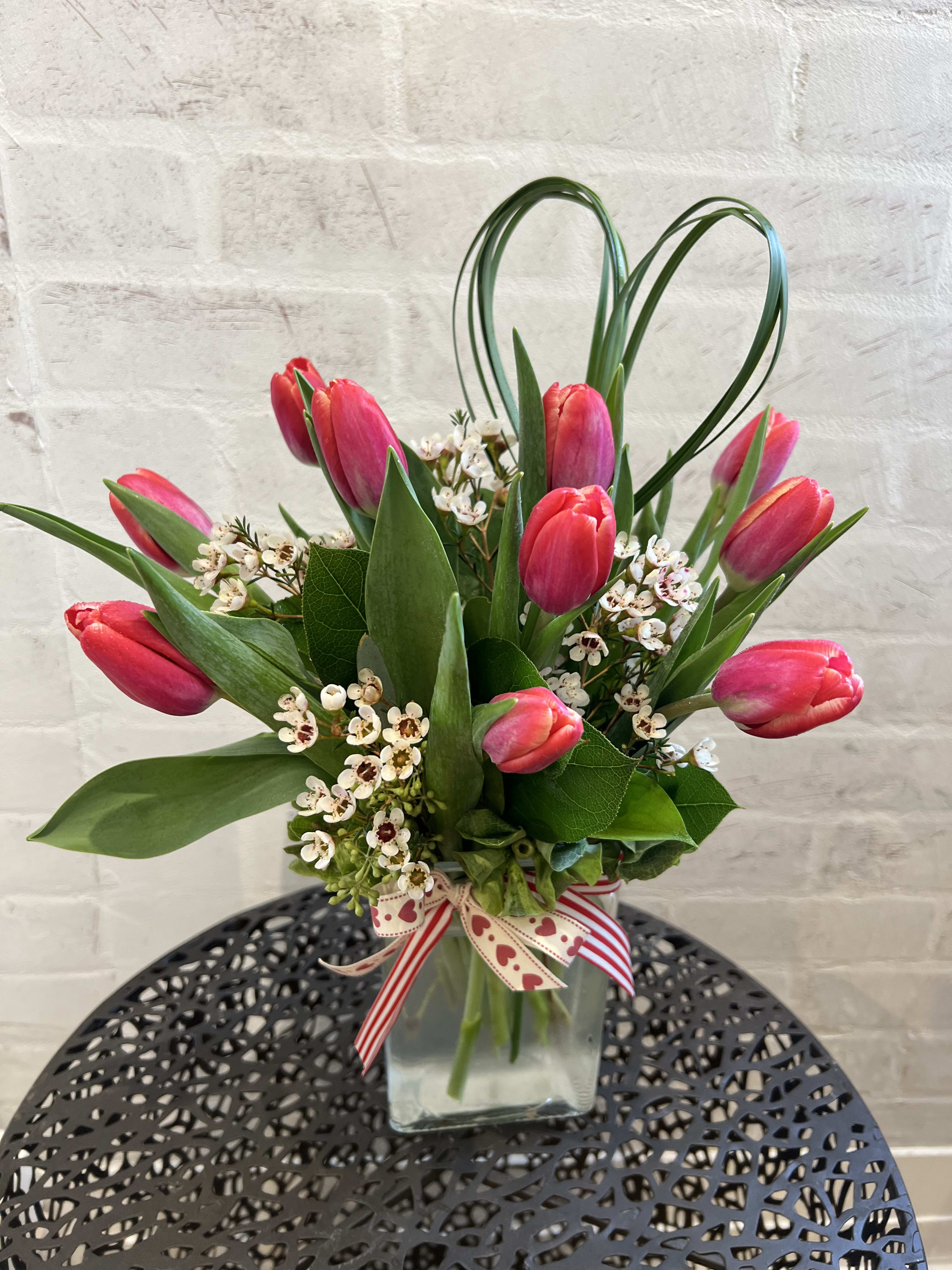 Two Lips  - A Valentine’s Day favorite! 10 RED double bloom tulips arranged in a rectangular glass vase with fragrant wax flower and a heart pick. 