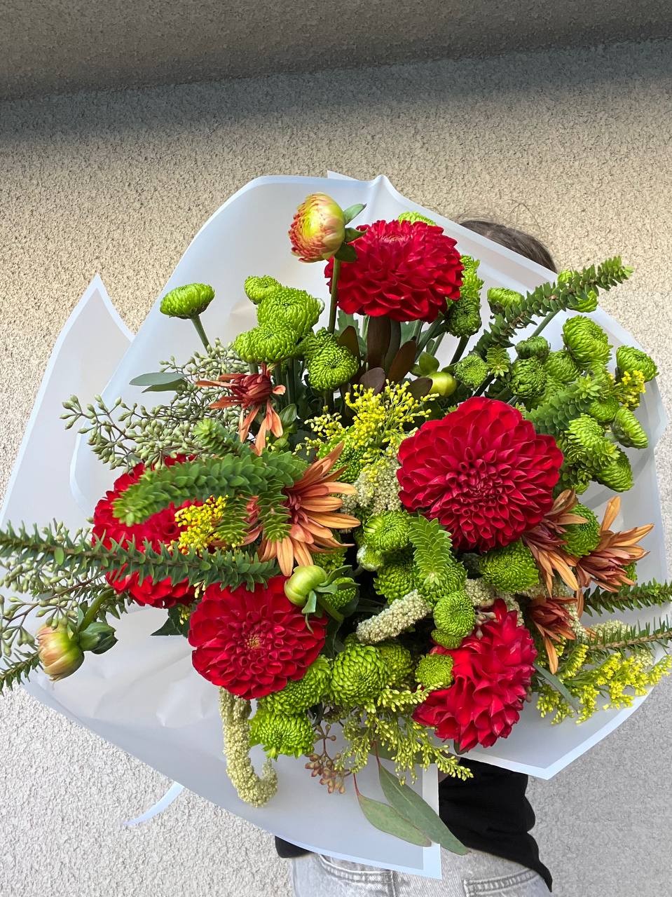 Vivienne - Bouquet “Vivienne” is the embodiment of elegance, passion, and natural harmony. Vibrant red dahlias symbolize energy and confidence, delicate green chrysanthemums add freshness, and warm orange accents bring a touch of coziness and sunlight. Graceful sprigs of greenery enhance the bouquet’s natural and airy feel.  “Vivienne” is a bouquet for those who appreciate style, sophistication, and the beauty of nature. It is perfect for a special occasion or as a sincere gesture of gratitude and love.