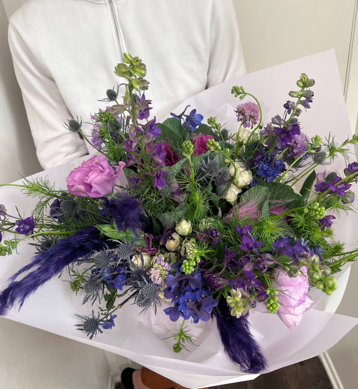 Hummingbird - Bouquet “Hummingbird” – Lightness and the Magic of Nature  This elegant bouquet captures the delicate beauty and vibrant energy of a hummingbird in flight. Deep shades of purple and blue intertwine with soft pink accents, creating a sense of lightness and sophistication. The rich textures and harmonious color palette give this arrangement a dynamic and enchanting look, making it a perfect choice for those who appreciate elegance and natural beauty.  