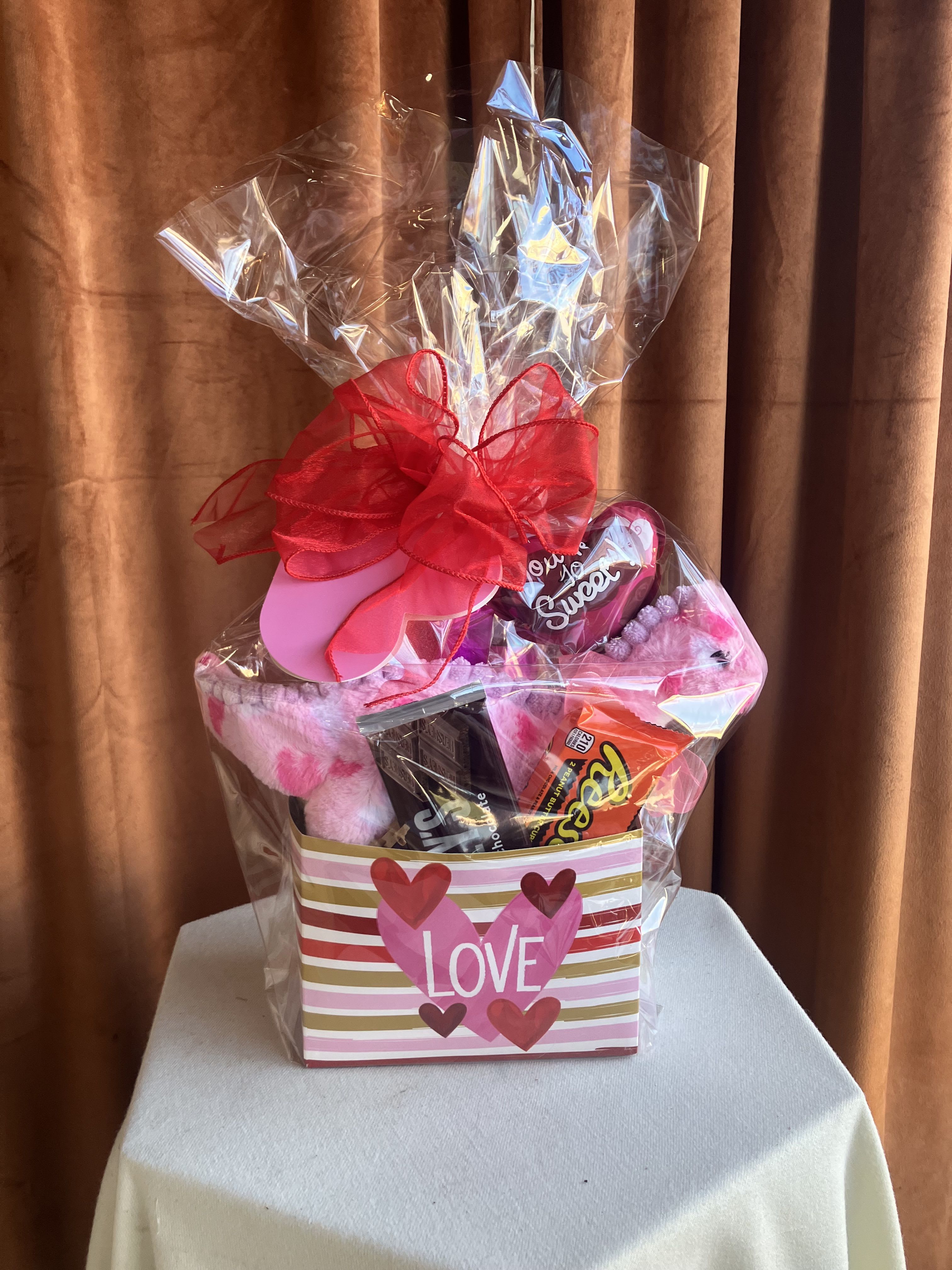 Valentine's Day Dinosaur  - This playful gift box features an adorable plush dinosaur paired with a fun assortment of sweet treats, all beautifully packaged for a cheerful surprise. Finished with festive ribbon and Valentine-themed accents, it’s a perfect mix of cuddly and fun.