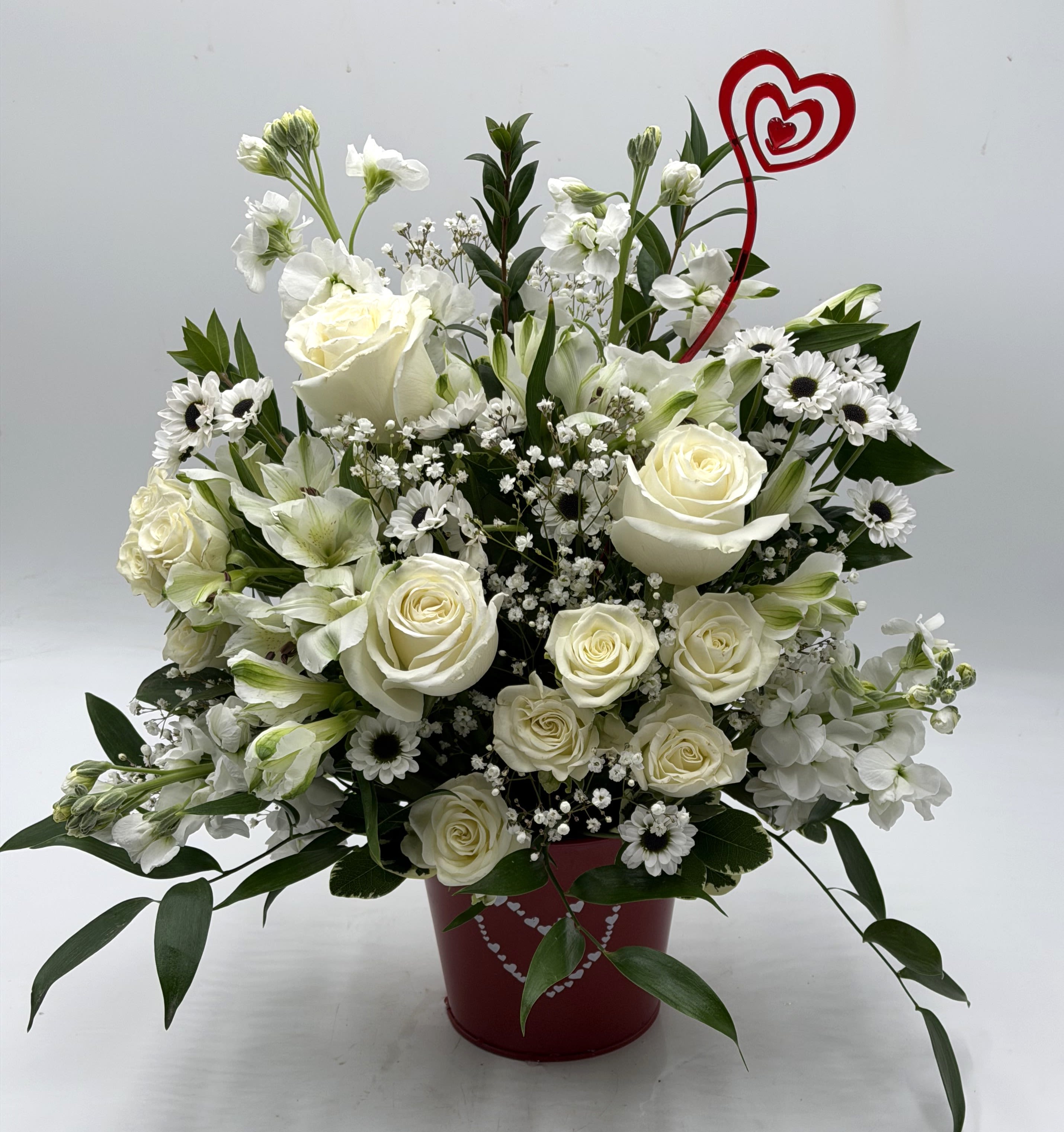 Purely Yours - A graceful Valentine's Day arrangement of creamy white roses, white spray roses, white stock and more designed in a festive red heart container. This bouquet is a timeless expression of pure love and devotion. 