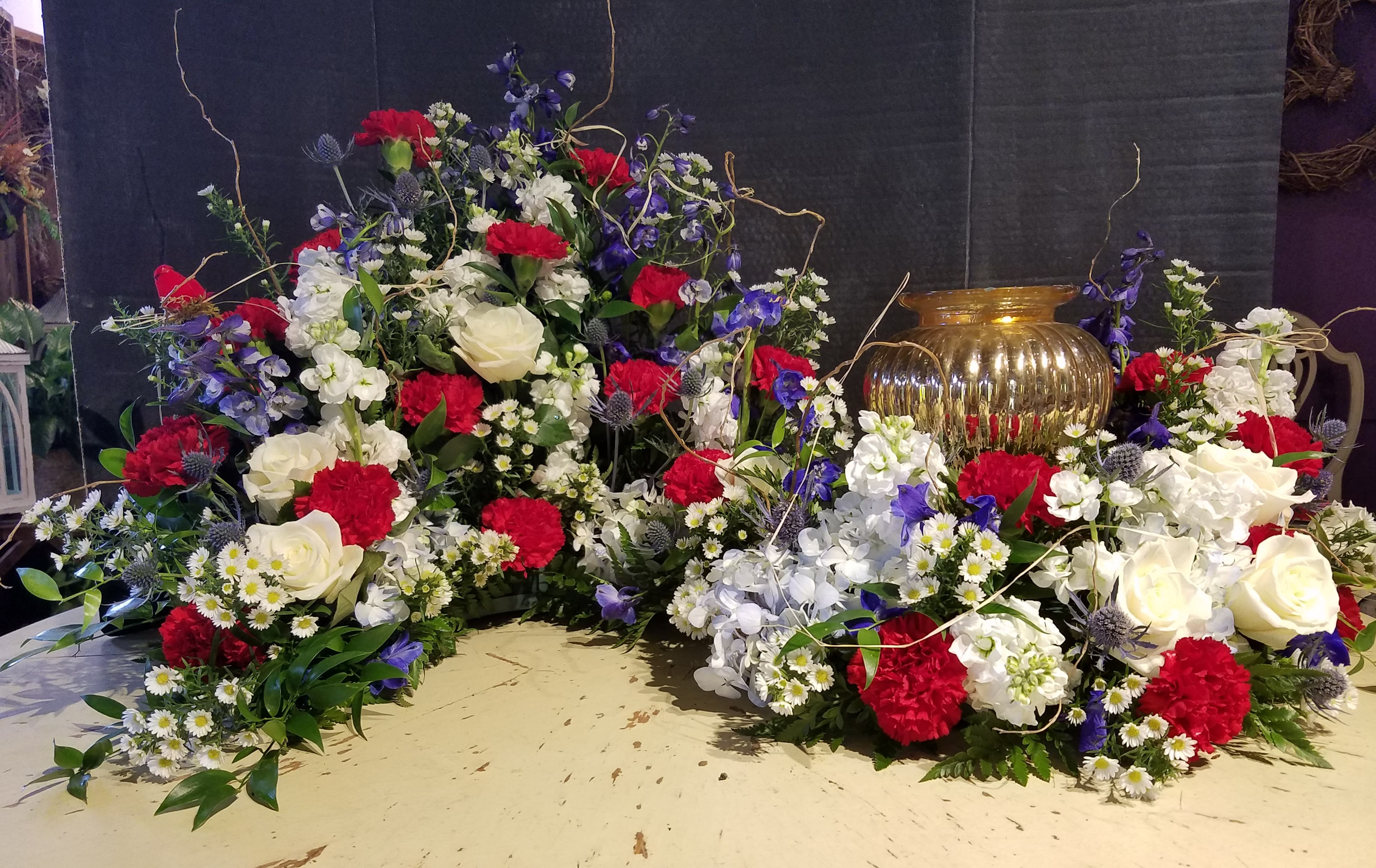 Eckert Florist's Cremation Urn Tribute  - This "S" shaped arrangement is created to incorporate any size Memorial Urn. To the left, space is provided for a cherished picture of your loved one. Picture shown in red, white, and blue colored flowers, but may be changed to fit your own personnel preference. Mixed seasonal colored flowers may also be chosen. *Please specify in order notes, special instructions, your color choice. *Urn not included     