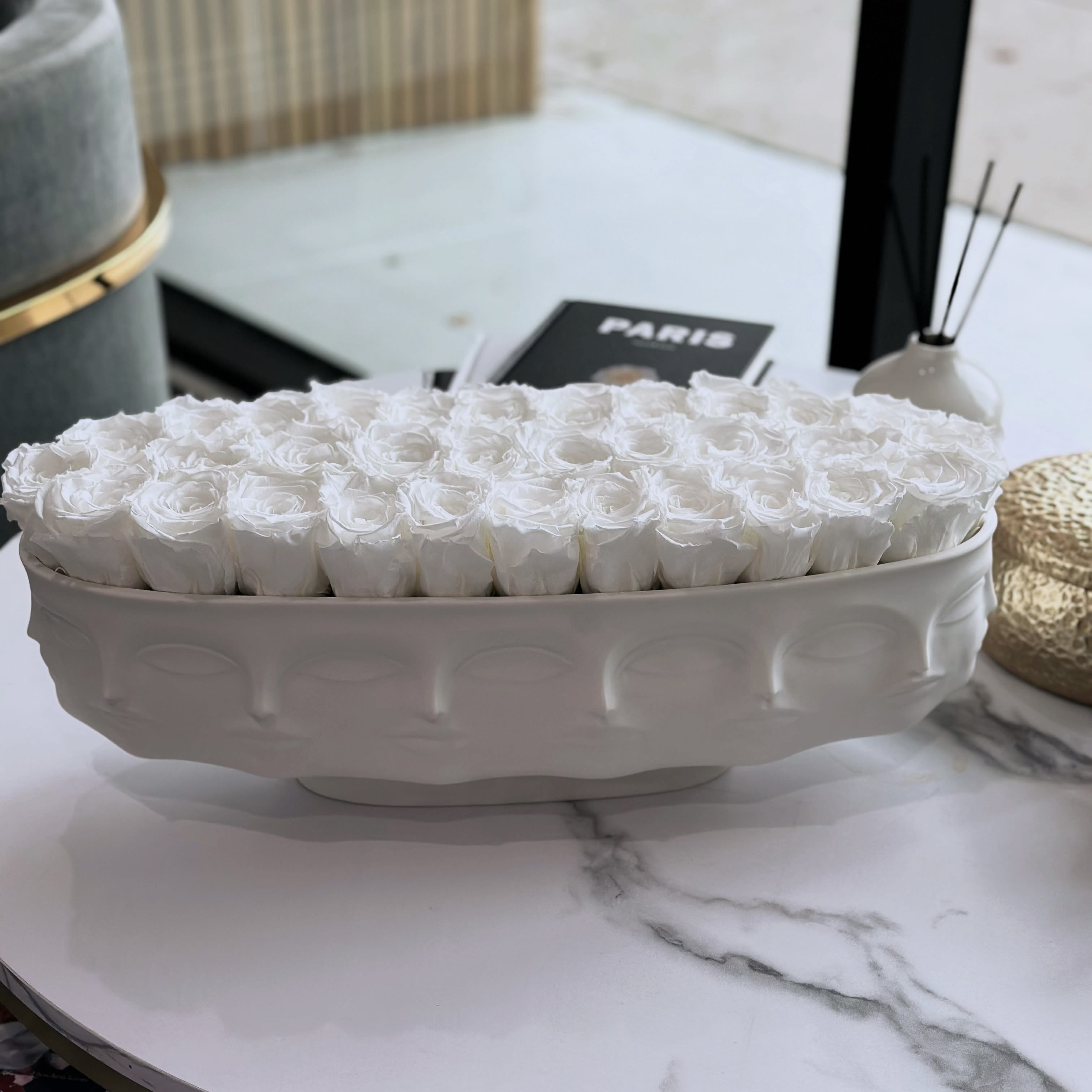 Dora ,preserved white (Jonathan Adler Collection) - The Jonathan Adler Designer Bowl vase with perpetual roses combines a sleek, modern ceramic vase with 30 white preserved roses. The arrangement combines timeless elegance with contemporary design, creating a beautiful, long-lasting floral display that requires little upkeep. Ideal for adding refinement to any setting.  Dora Maar Long Bowl can be purchased separate for $695  Jonathan and his team sculpt the models for our Muse pottery and then substitutes our signature geometric relief patterns with body parts—faces, breasts, lips—to create a surreal style. Pieces are inspired by our favorite artists' muses. 