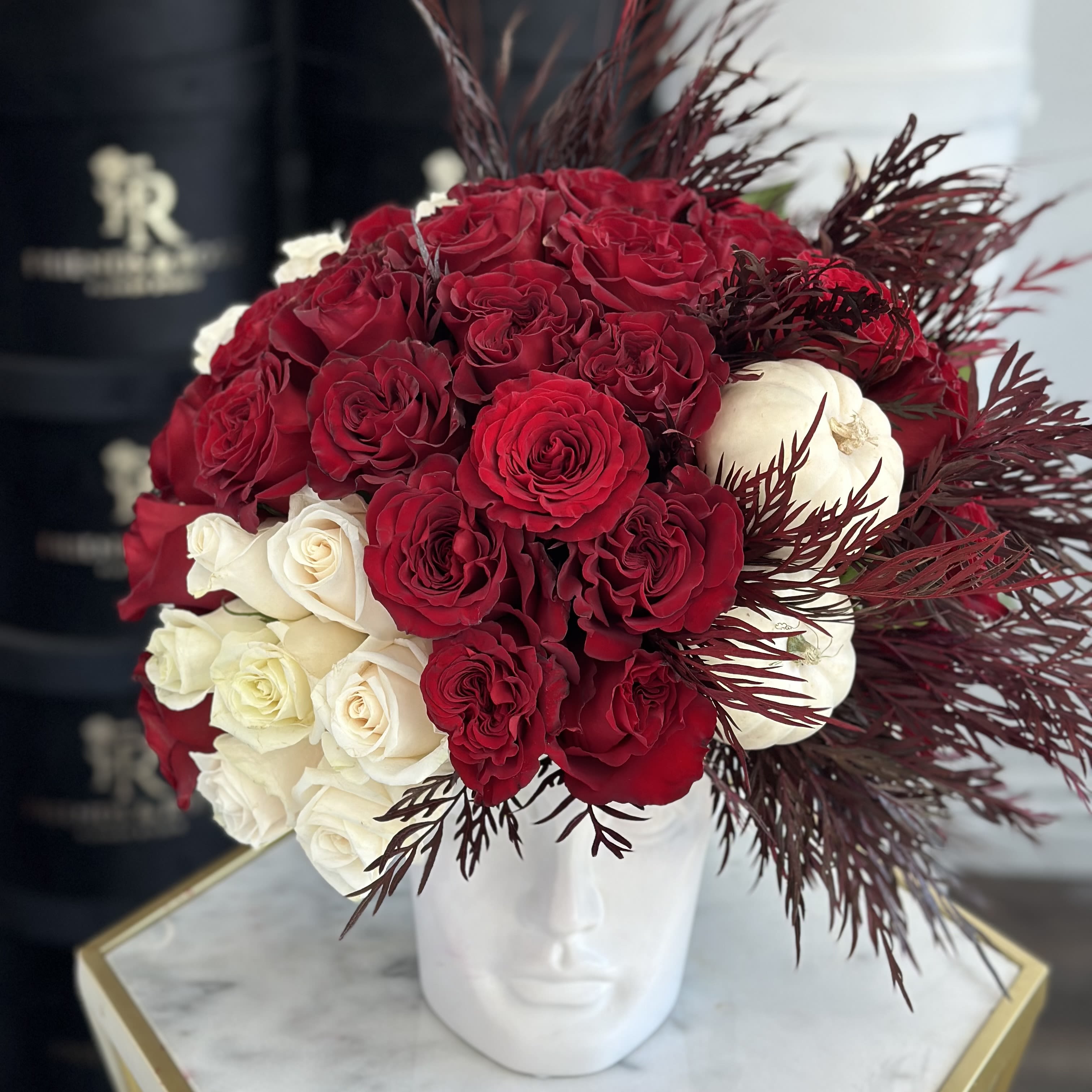 Valentina - As elegant head vase filled with around 45 roses, complemented by greens an pumpkins. This arrangement can bring warmth, color, and a touch of elegance to your home.