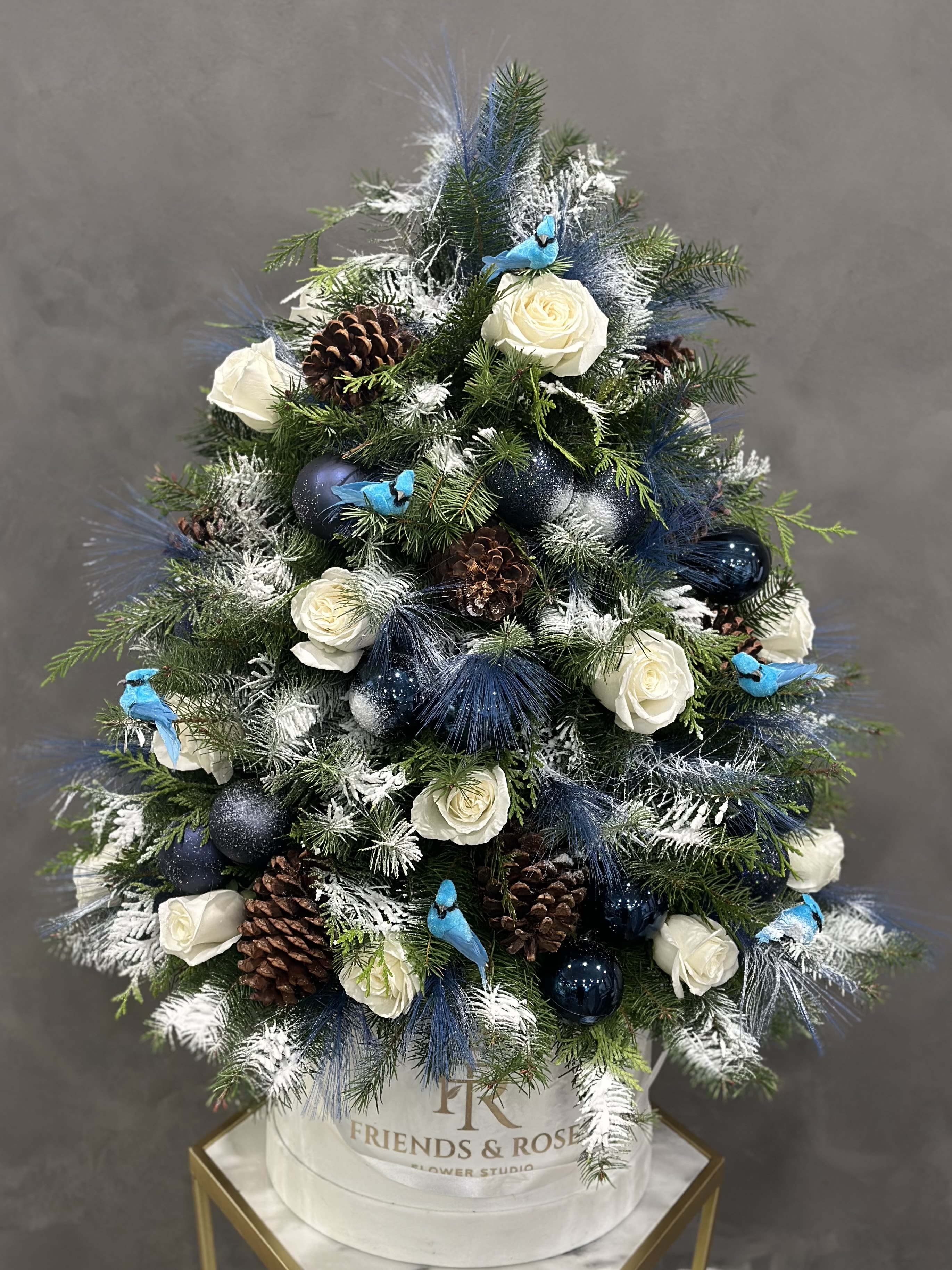 Winter Wings Tree - Our large white signature box has a lovely Christmas tree arrangement, with white roses, Christmas tree branches, cones, miniature birds, and other ornaments. Our top florist created a masterpiece. A wonderfully unusual gift for your family members or house decor.  