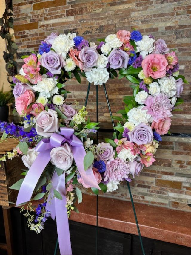 Lavender Garden Heart - A tender and classic tribute to a precious life. Heartfelt emotions and sympathies find delicate expression here. Lovely flowers such as light pink roses hydrangea and miniature carnations mix with lavender button spray chrysanthemums.