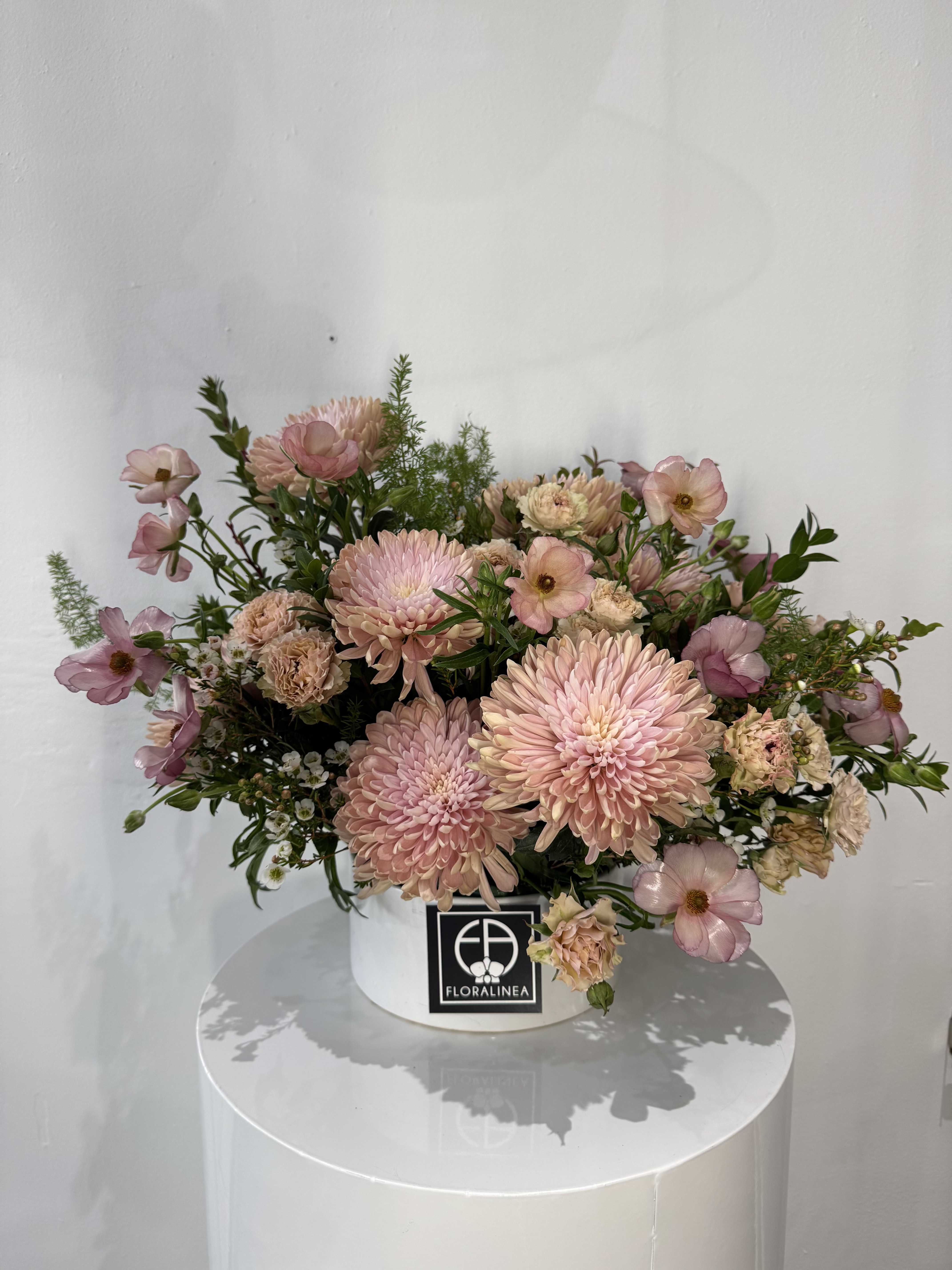 The It Girl - The perfect mix of peaches and pinks, spray roses, butterfly ranunculus, greens and wax flowers will elevate this arrangement to be the perfect gift or accessory to your home.