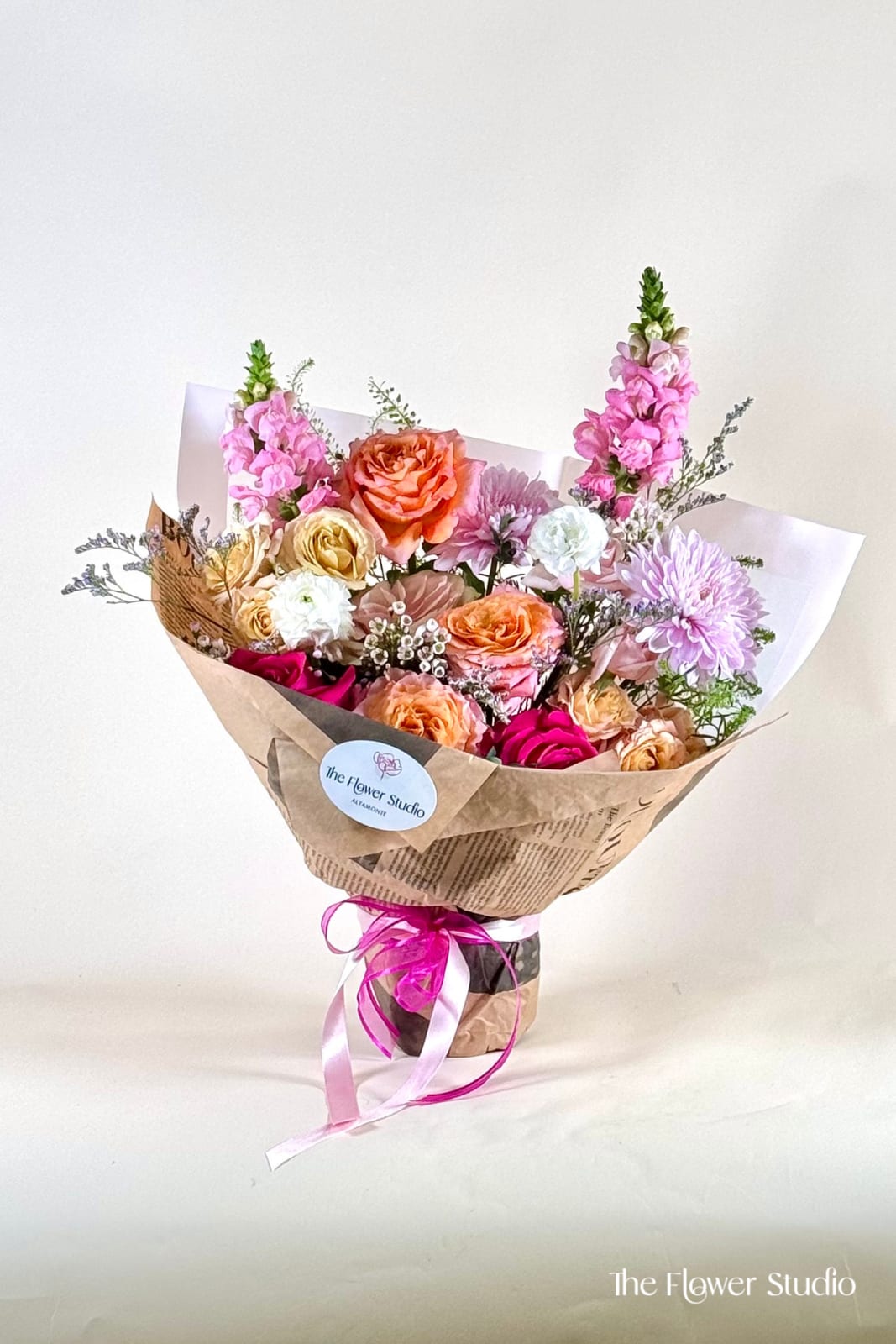 Blush Babe - A soft and romantic hand-tied arrangement designed with a lush mix of blush, peach, cream, and vibrant pink tones. This bouquet features layered textures, gentle movement, and airy accents that create a garden-inspired, elegant feel. Wrapped in natural paper and finished with a delicate ribbon, it’s perfect for celebrating love, gratitude, or simply brightening someone’s day. Flowers and wrapping paper will vary depending on color preference and seasonal availability, ensuring each arrangement is uniquely designed.