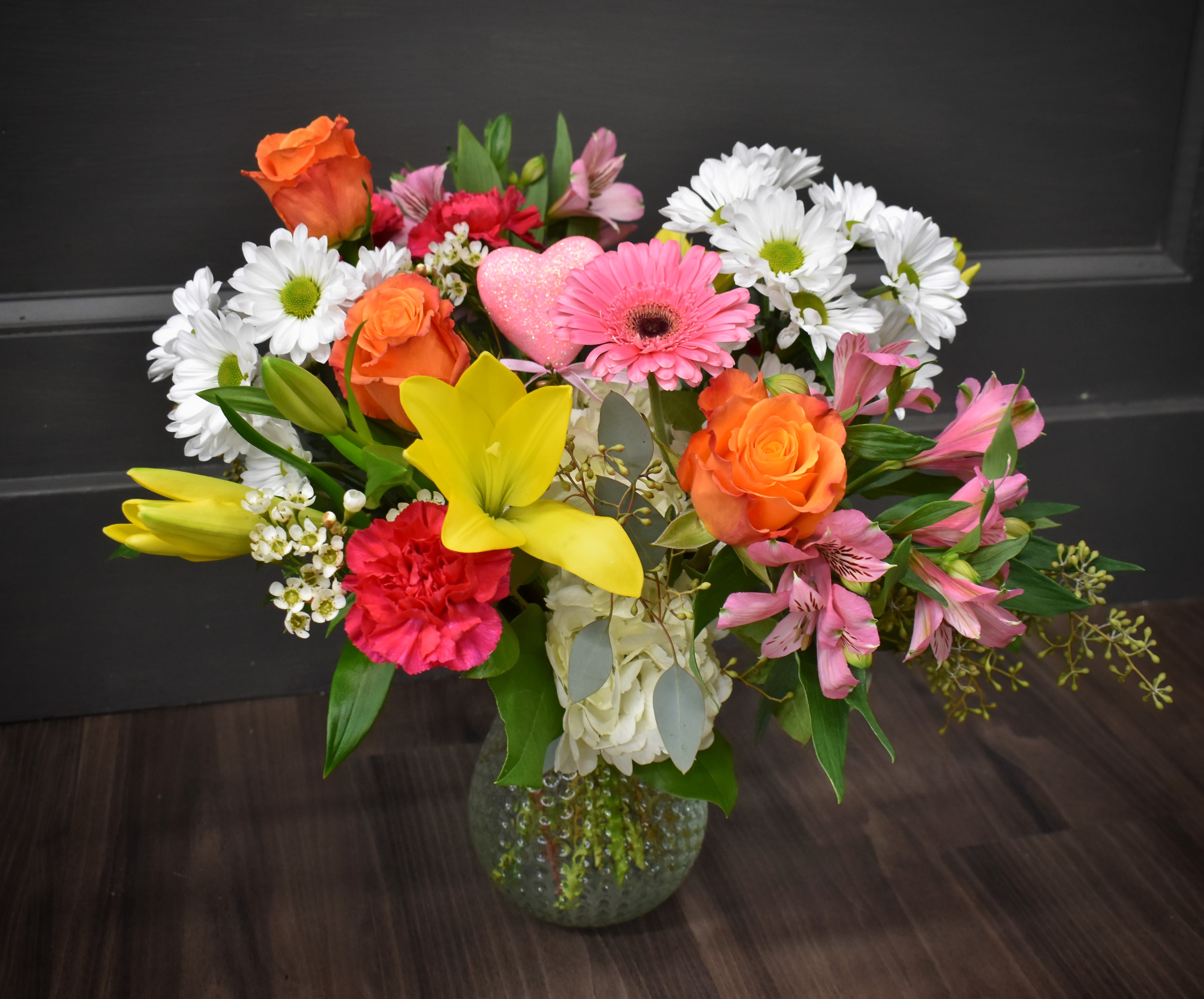 Designer's Choice with Roses  - The rose, symbolizing love and passion, is complemented by lush greenery and a collection of other bold, vibrant flowers, creating a perfect balance of elegance and romance.