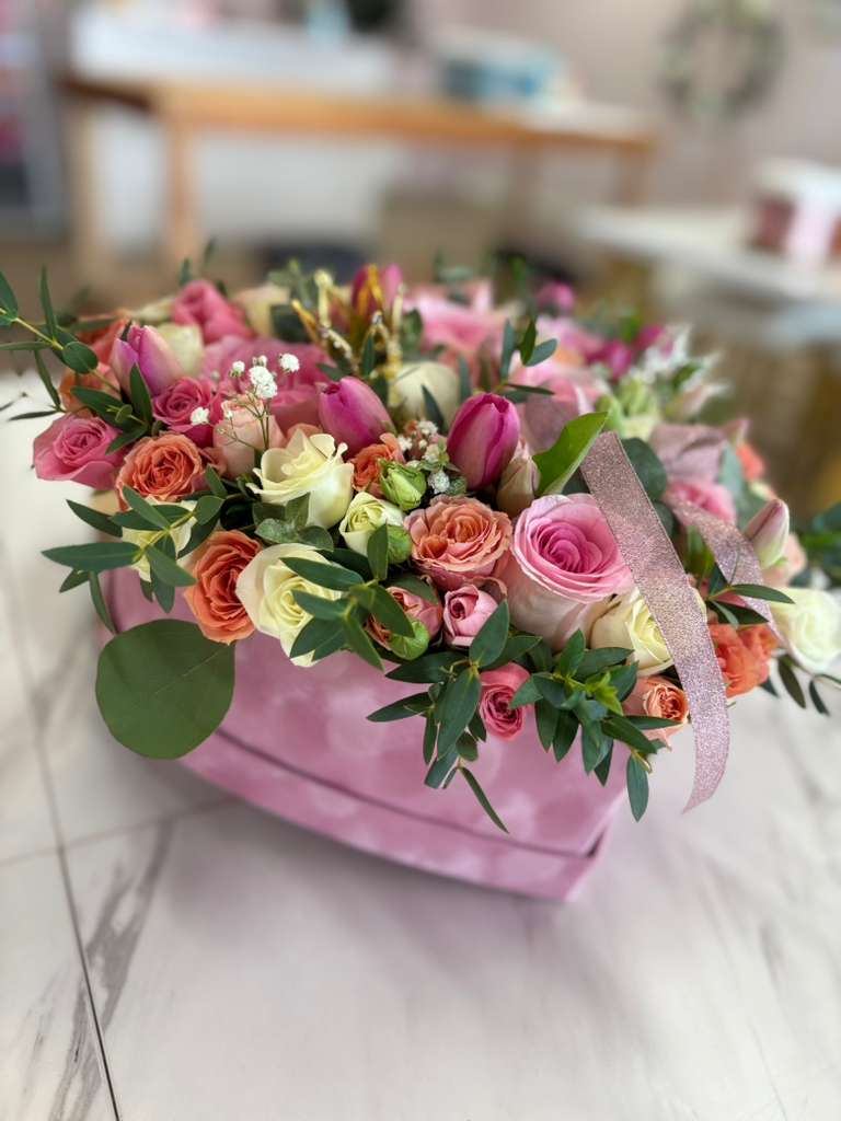 Heart Box of Roses and Tulips – Premium Romantic Arrangement - An elegant and loving design. This heart-shaped box is carefully crafted with fresh roses and mini roses in shades of pink, peach, cream, and red, accompanied by natural foliage and delicate details. The velvety pink box with a shiny bow adds the perfect touch of elegance and tenderness, ideal for expressing love, gratitude, or admiration. Perfect for anniversaries, birthdays, Valentine's Day, or simply to surprise someone special.  Includes special hydration for longer life.  11.8" x 10.6" x 4.7" 