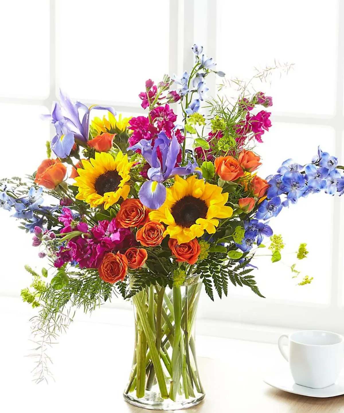 RAYS OF LIFE - Show your loved ones how much you care about them with a beautiful bouquet full of bright summer florals. Our Rays of Light™ Bouquet arrives handcrafted by a local florist with sunflowers, iris, stock and delphinium to offer your comfort. While this bouquet is stunning in size, it is best suited for a small table, or within a home or residence. *** VASE WILL VARY ***