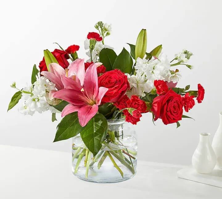 The Starstruck Bouquet - THE STARSTRUCK BOUQUET With an abundant blend of roses, carnations, and LA Hybrid lilies in a cinched glass vase, this captivating arrangement is sure to make them feel like they belong on the red carpet. Please Note: The bouquet pictured reflects our original design for this product. While we always try to follow the color palette, we may replace stems to deliver the freshest bouquet possible, and we may sometimes need to use a different vase. *** VASE WILL VARY**