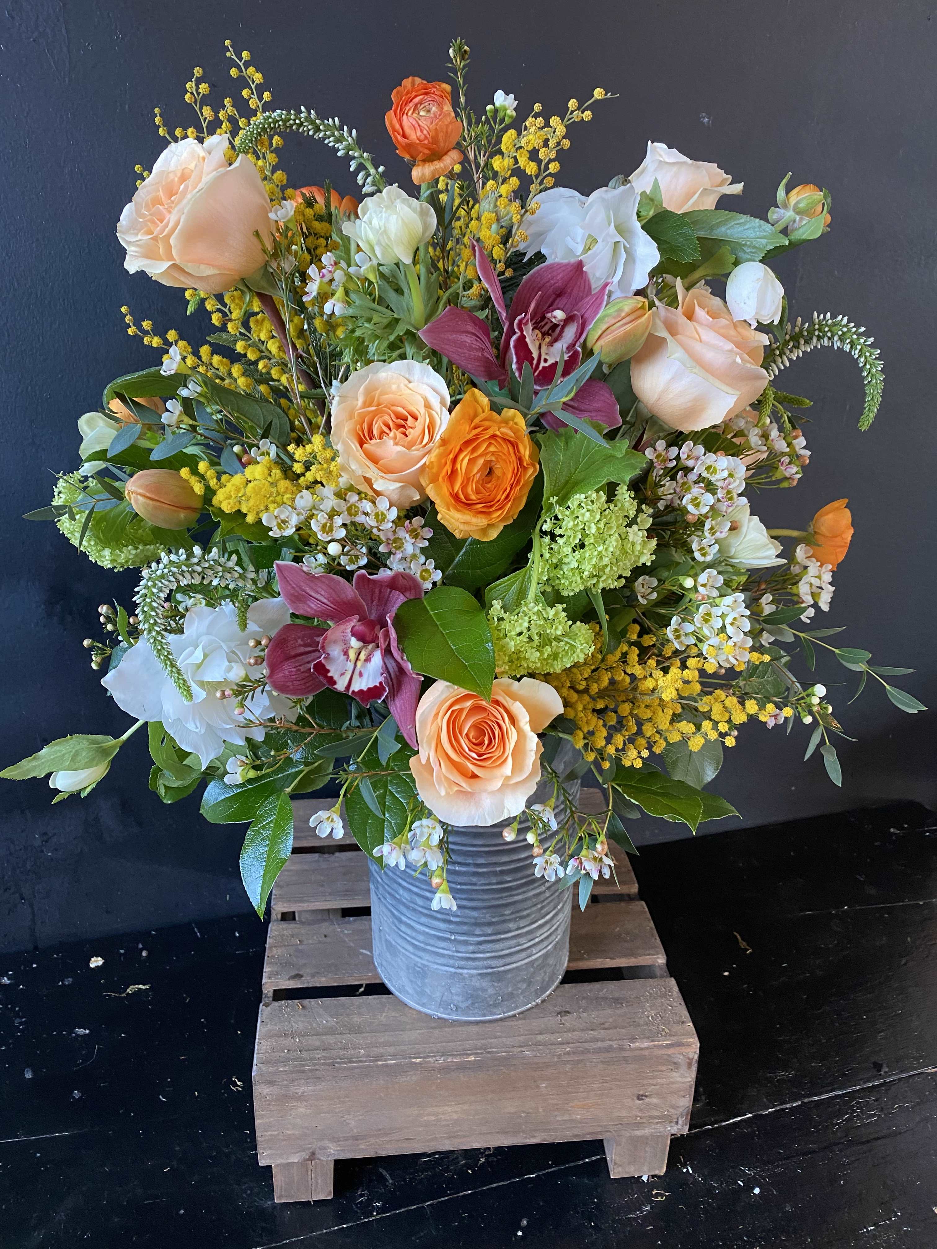 Lavish Farm Vase - Large vase style arrangement in a specialized container featuring roses, ranunculus, helleborus, and other designer blooms.