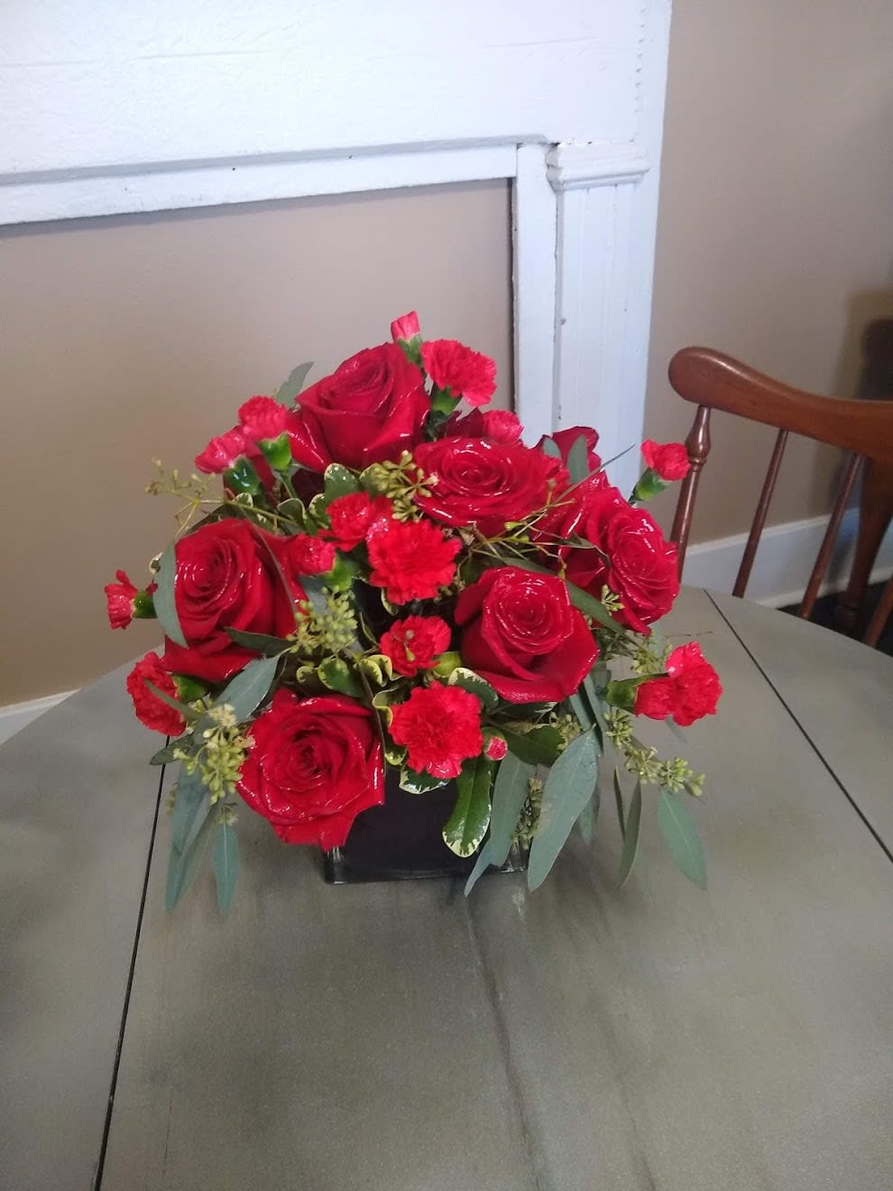 Rosy Red Love Cube - Red is the color of love. A red short cube vase filled with red roses, red mini carnations,  and mixed greens. Packed full of love for that special someone. Add a balloon and a box of chocolates and make your gift of love even sweeter.