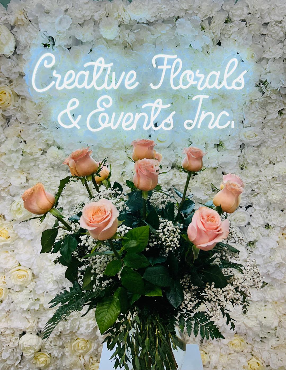 V131 - A dozen peach roses arranged in tall clear glass vase with mixed greenery and filler to accent. 