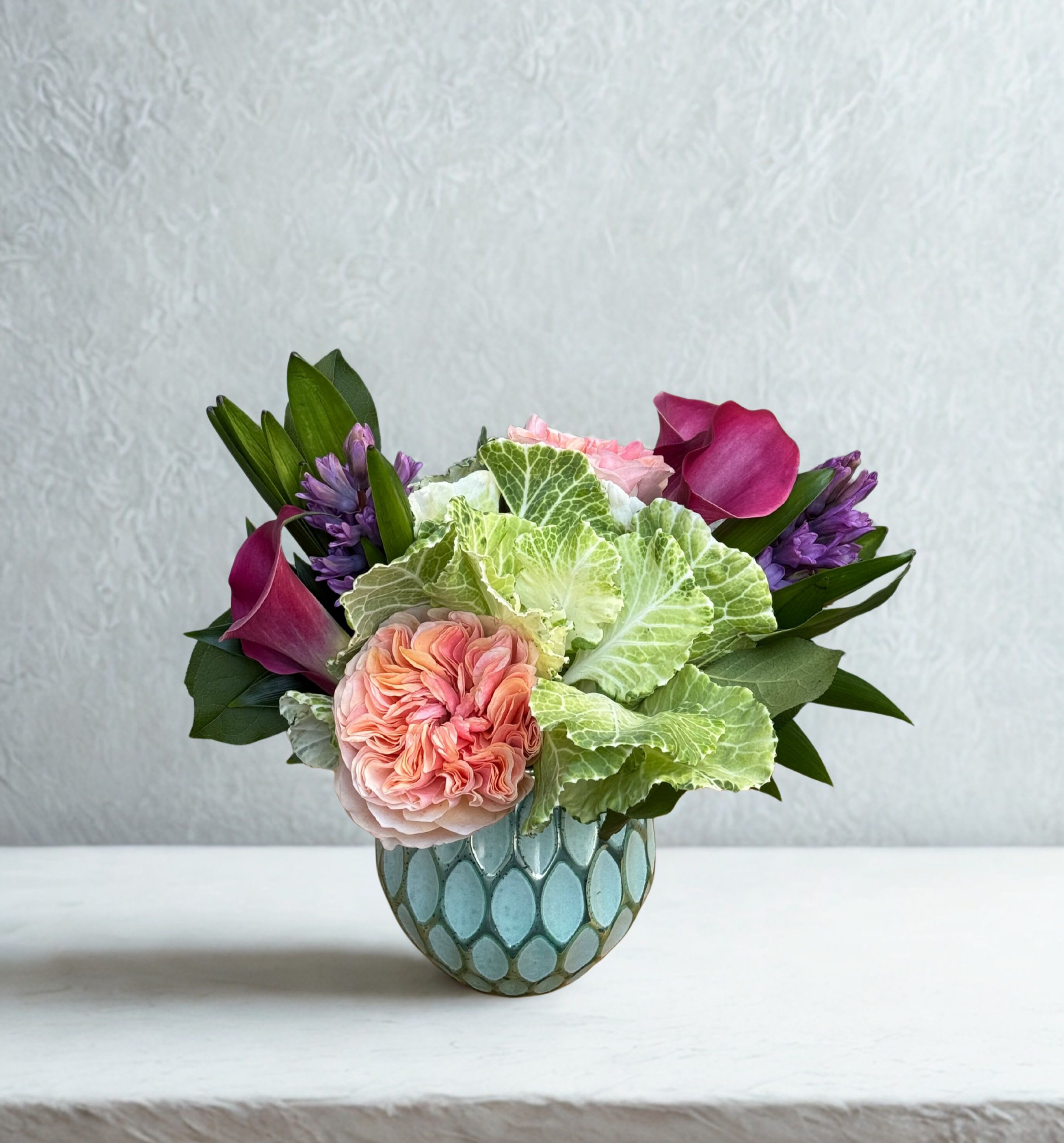 Hillsides Blush &amp; Velvet - Romantic peach and blush roses mingle with deep violet accents and fresh greenery in this heartfelt design. Thoughtfully arranged in a patterned blue vase, it’s perfect for celebrating love, connection, and meaningful moments.