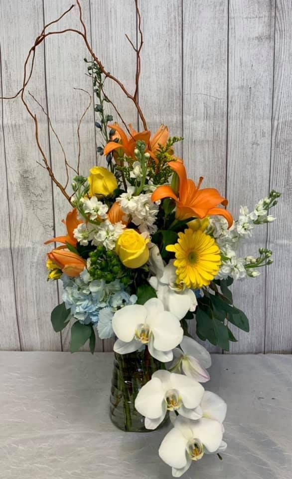 CFB110 - A tall showy vase of high end flowers such as roses, hydrangeas, lilies and other blooms in white, orange and yellow. 