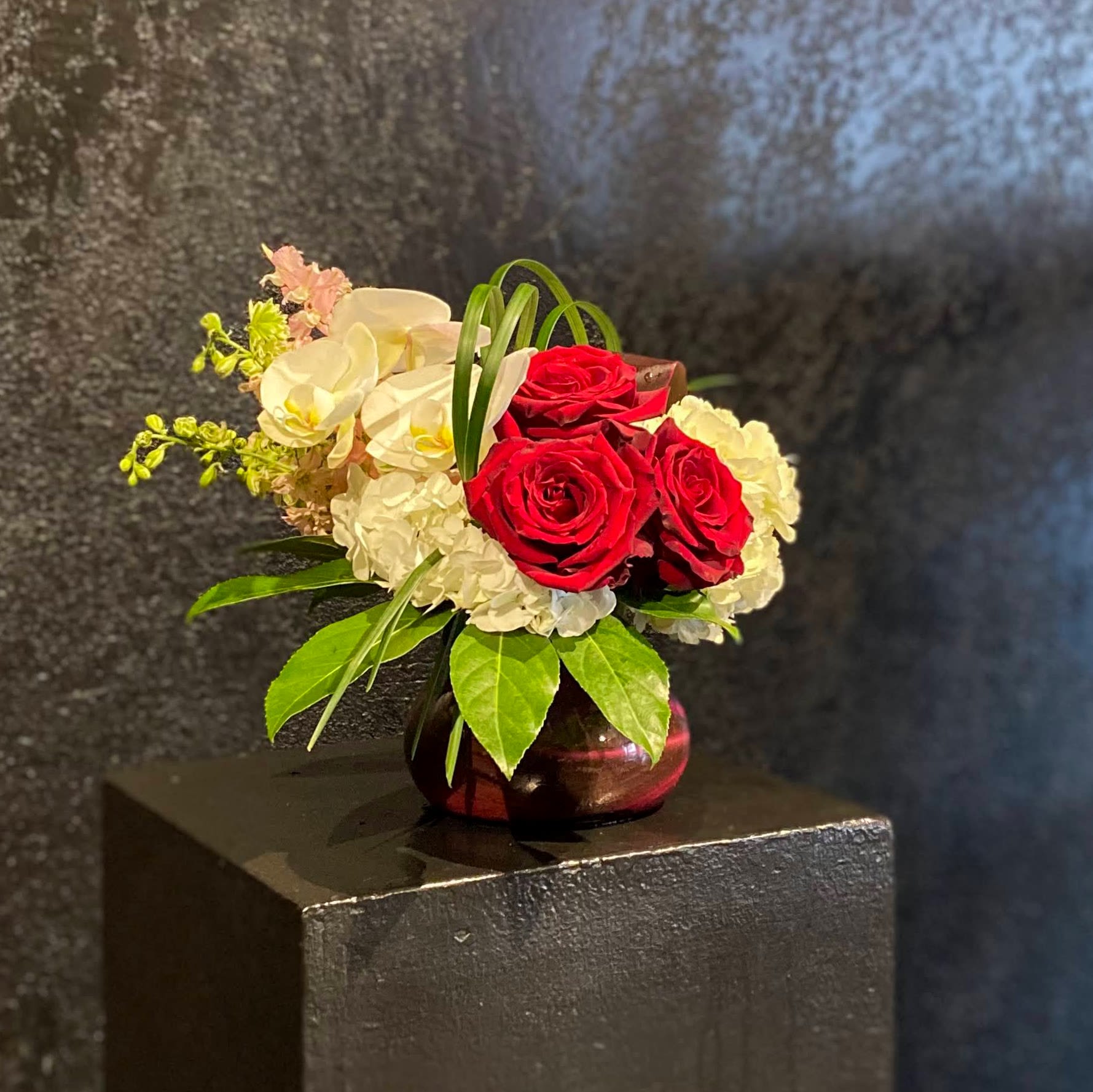 #49 You Drive Me Crazy - The perfect posy vase holds a cluster of red roses accented by pink and white flowers such as hydrangea and orchid blooms. It's the perfect gift for them to keep at their desk; container measures approximately 5x5"