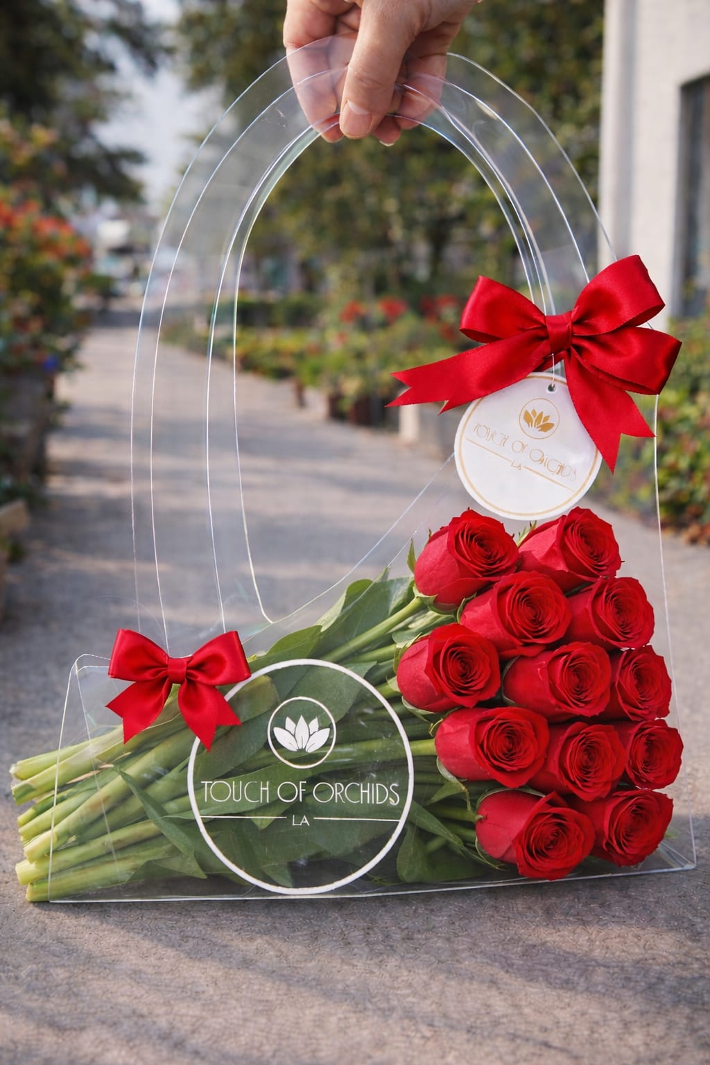 Red Rose  Purse  - Classic Red Rose Acrylic Purse Arrangement Bold, timeless, and unmistakably romantic, this classic red rose arrangement is designed in a clear acrylic purse for a striking modern statement. Featuring premium long-stem red roses, accented with elegant satin bows and Touch of Orchids LA signature branding, this luxury floral handbag is perfect for Valentine’s Day, anniversaries, proposals, or unforgettable romantic gestures.  Designed for those who appreciate modern luxury flowers, this red rose purse arrangement delivers high-impact elegance and makes a stunning keepsake long after the blooms fade. Available for luxury flower delivery throughout Los Angeles.