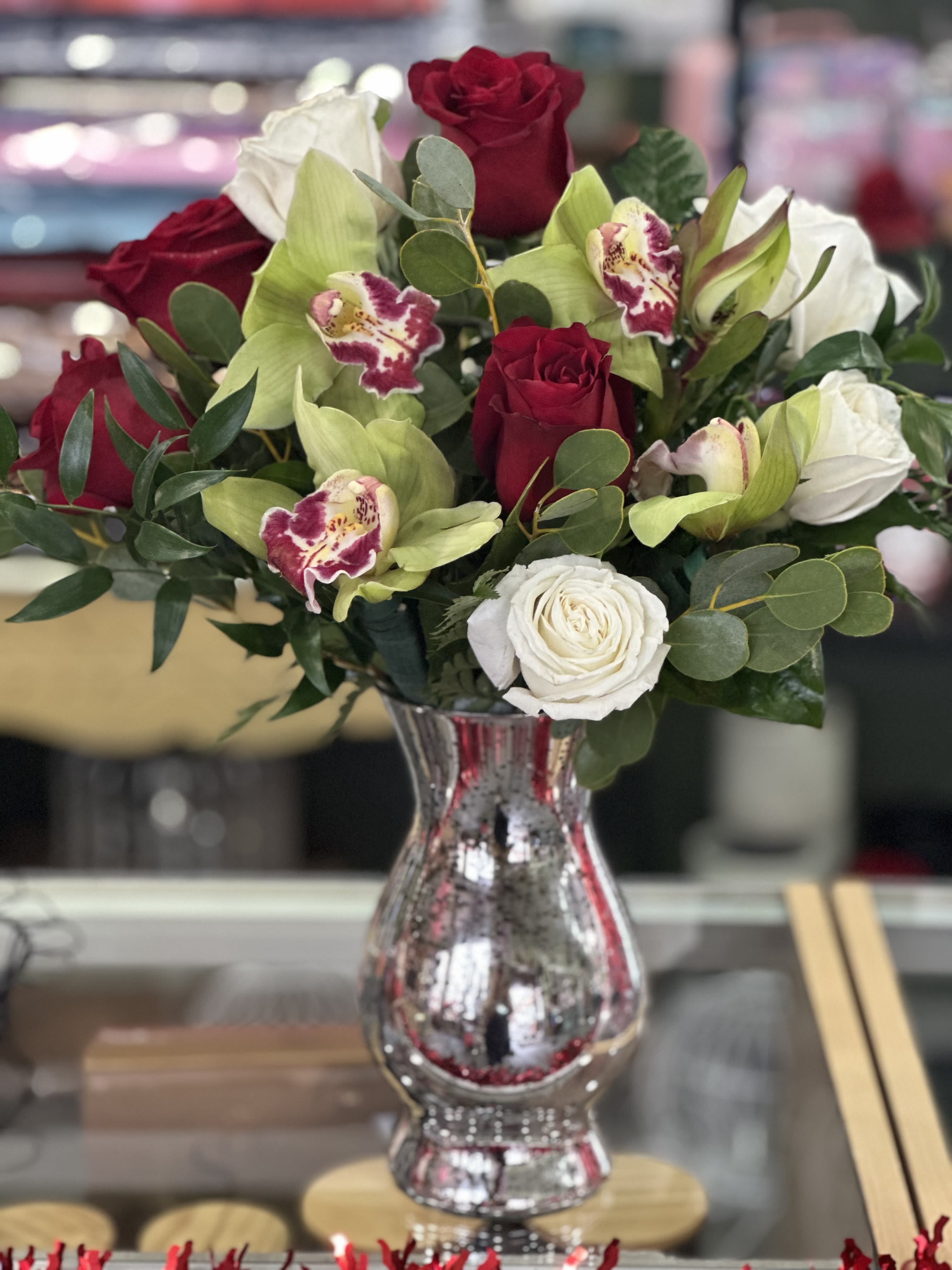 Roses and orchids  - Velvet red roses and white roses together with orchids formed this beautiful elegant design.  Silver vase. Greens and filler. 