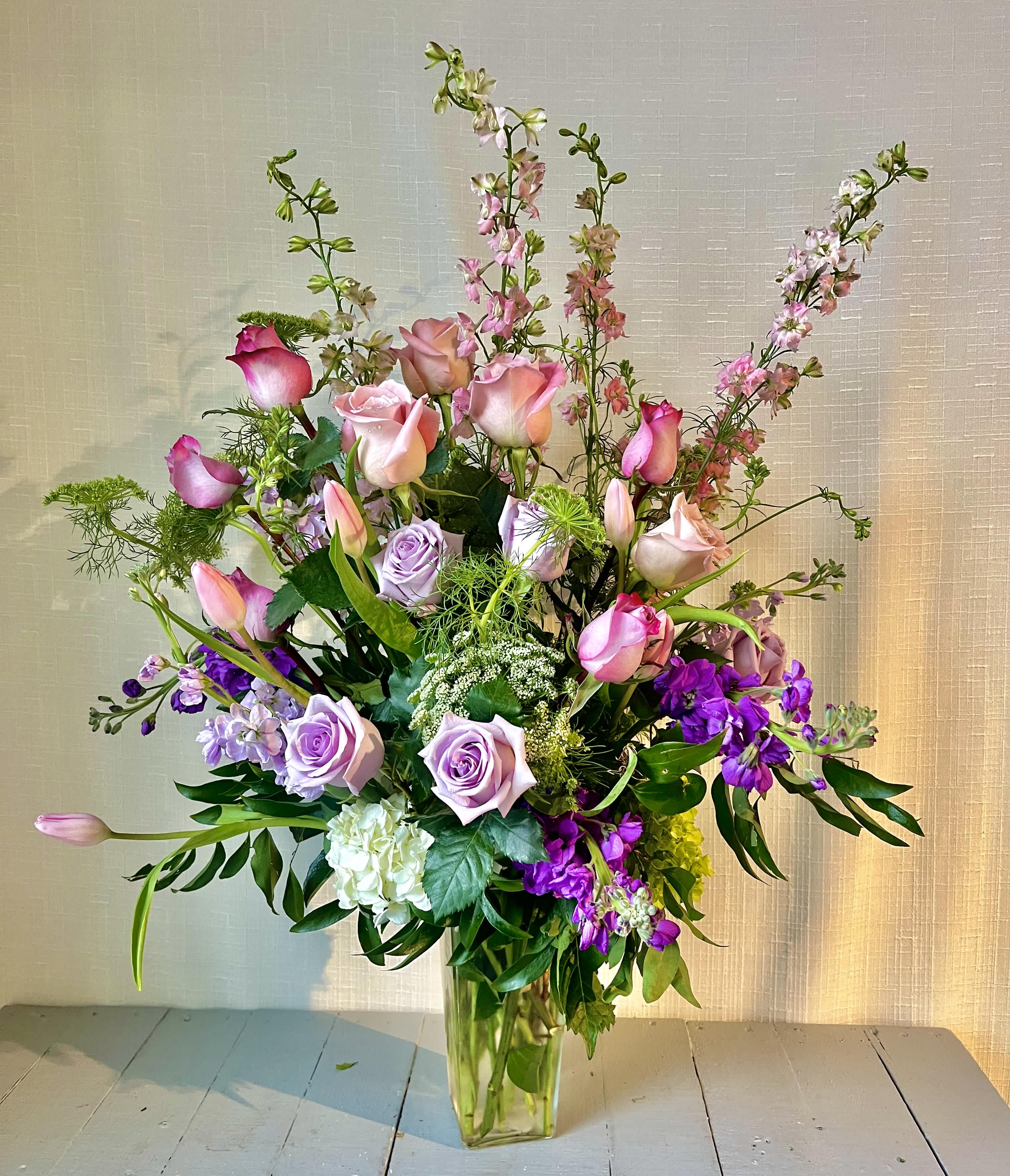 Purple Delight - "Purple Delight" is a lush collection of purple and white flowers with foliage designed in a clear vase.  For even more of an impact, allow us to upgrade your design to a Deluxe or Premium version, which will feature a larger quantity of stems and larger vase.  *Content may vary*