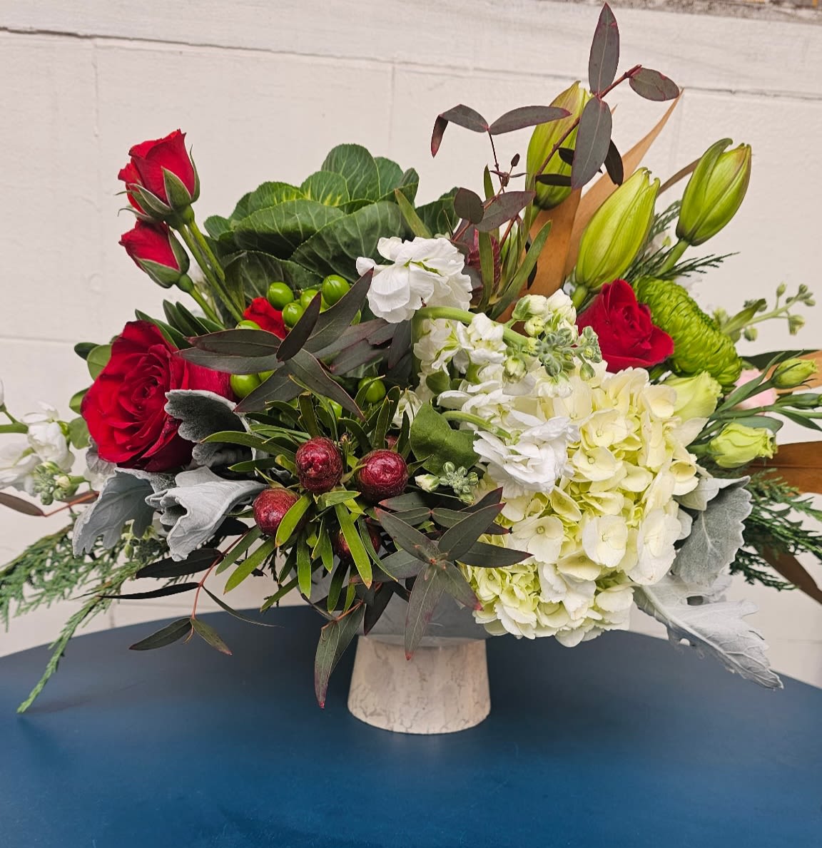 Christmas love - A beautiful centerpiece made of fresh hyadrangea, red roses, white lylis and beautiful Christmas greens.