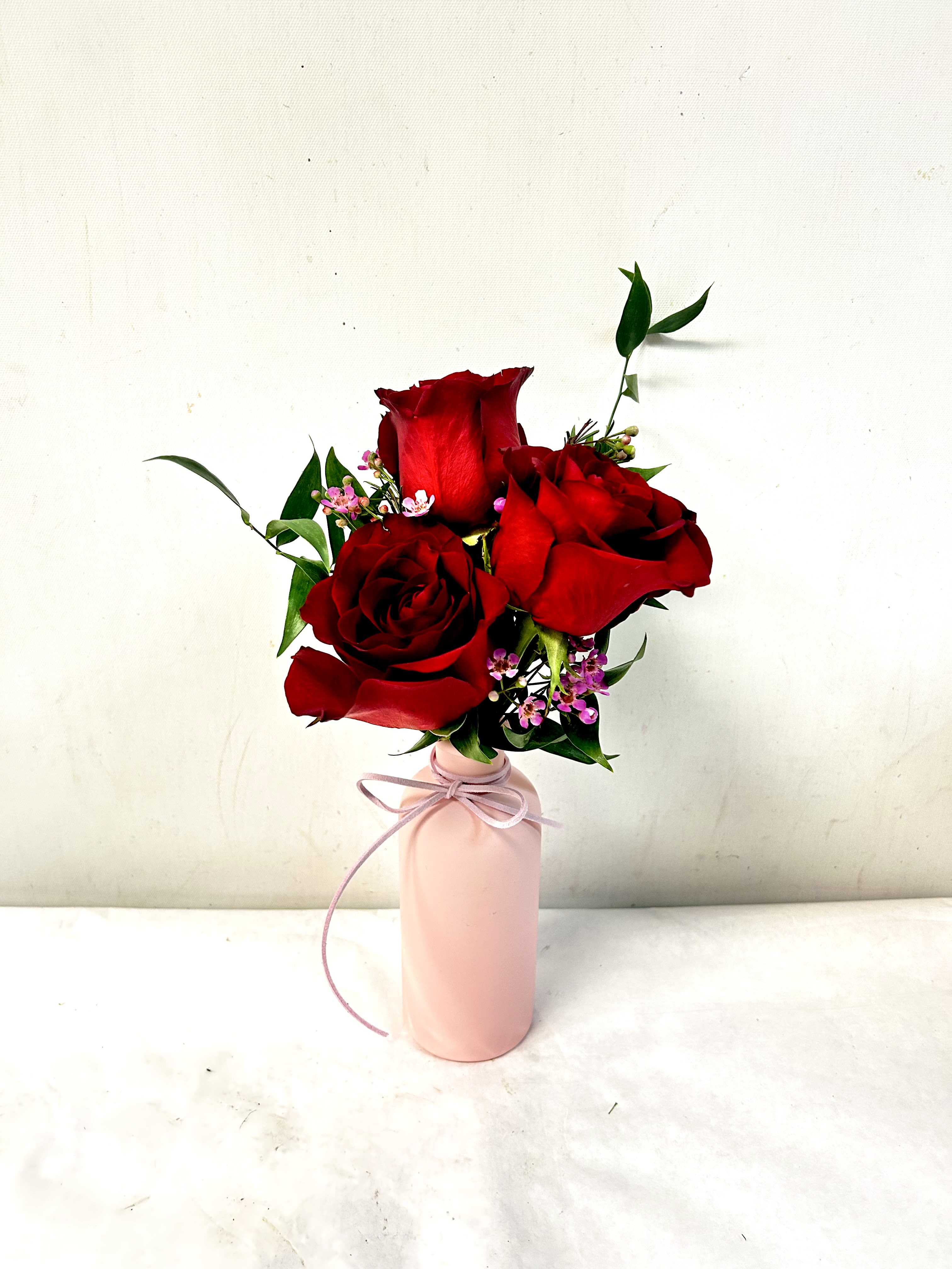 Charm - Add a touch of classic romance with this stunning trio of deep crimson roses. Accented with delicate purple waxflower and slender greenery, this arrangement is perfectly nestled in a soft pink bud vase and finished with a matching satin ribbon. It is an ideal gift for an anniversary, a birthday, or just to show someone you care.