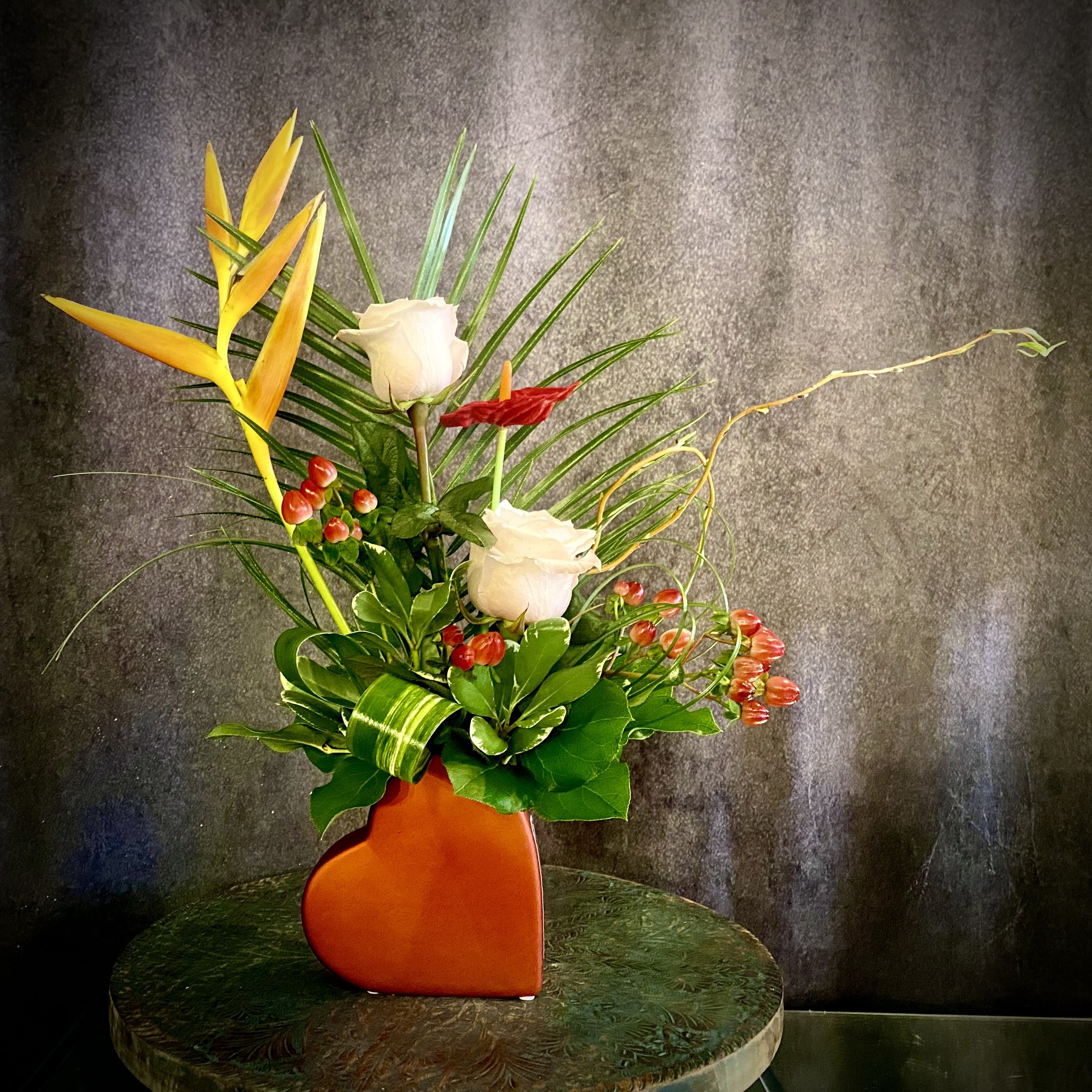 Unique Love - For the love that is one of a kind- A beautiful &amp; unique flower design. Includes an assortment of tropical and garden flowers in a unique heart shaped vase. Includes Heliconia, Roses, Berries, accents of tropical foliage, and a faux red red keepsake Anthurium. 