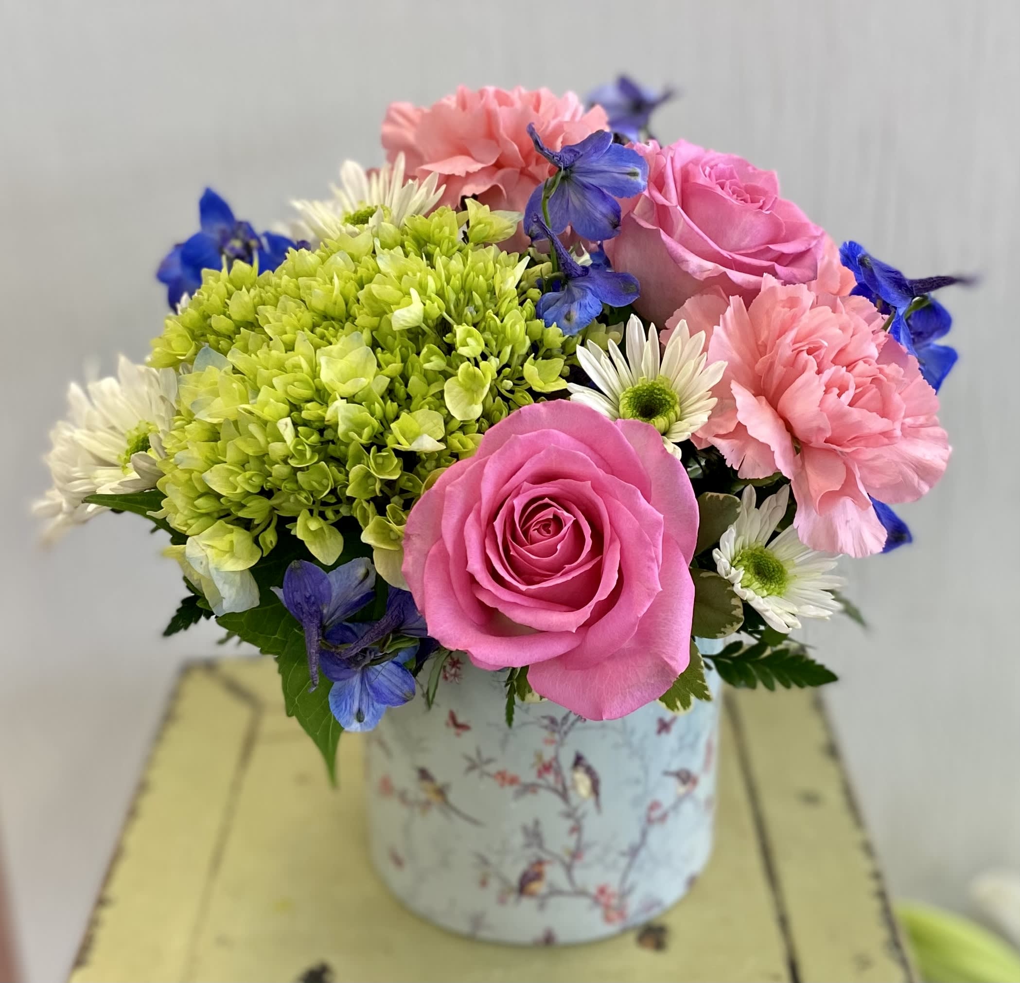 Sunny Day Blooms - A lovely mix of flowers in a novelty container. Decorative  container will vary.