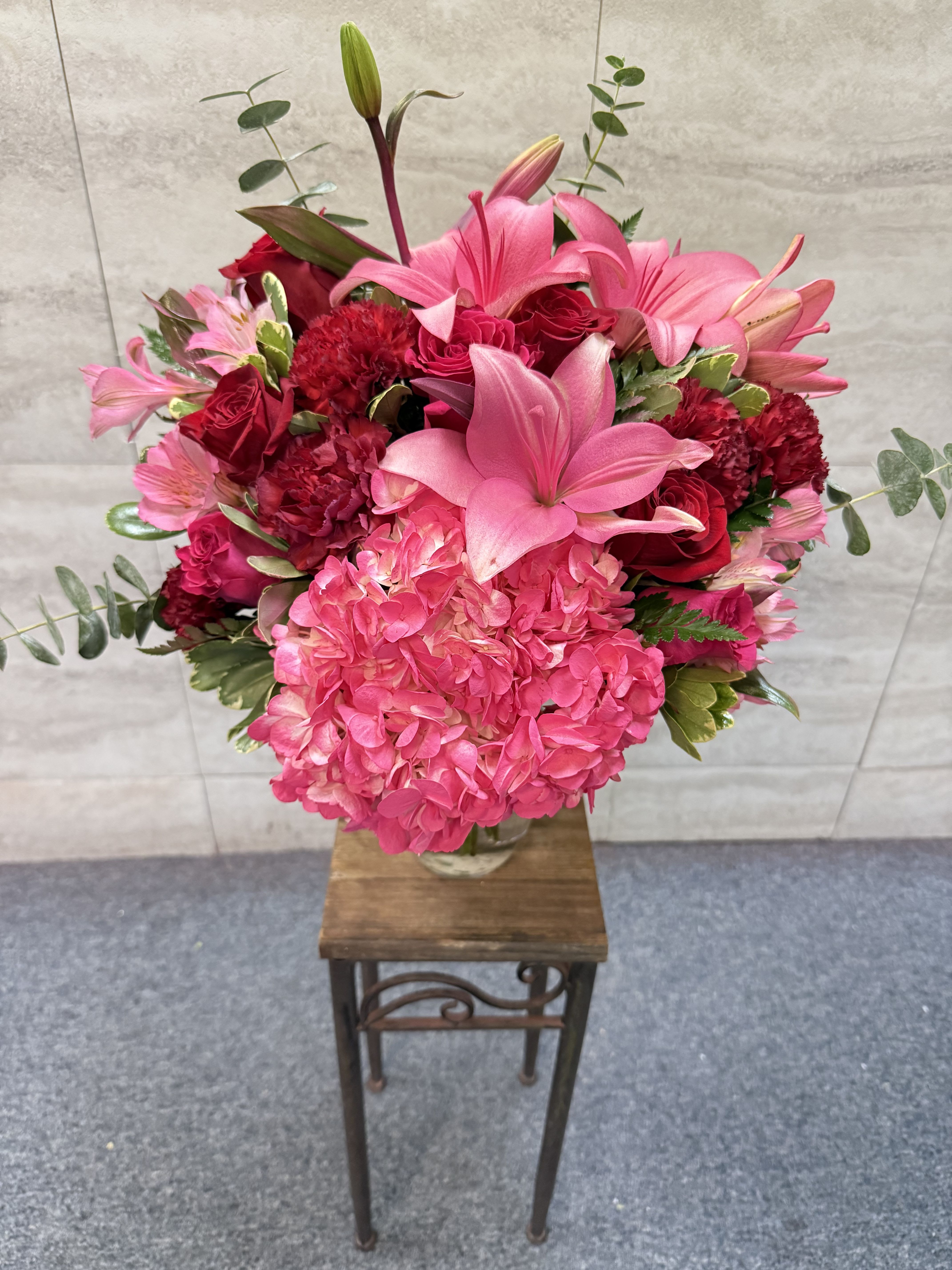 Love struck  -  is a bold, romantic arrangement that wears its heart on its sleeve   A lush blend of hot pink hydrangea, vibrant pink lilies, deep red roses, and richly textured carnations creates a feeling that’s equal parts passion and tenderness. Soft blush accents and fresh eucalyptus add movement and contrast, giving the design depth and a just-picked elegance.  Overflowing with color and emotion, *Love Struck* feels like a love letter in floral form—perfect for grand gestures, anniversaries, or anytime you want to say *“my heart is yours”* without holding back. 