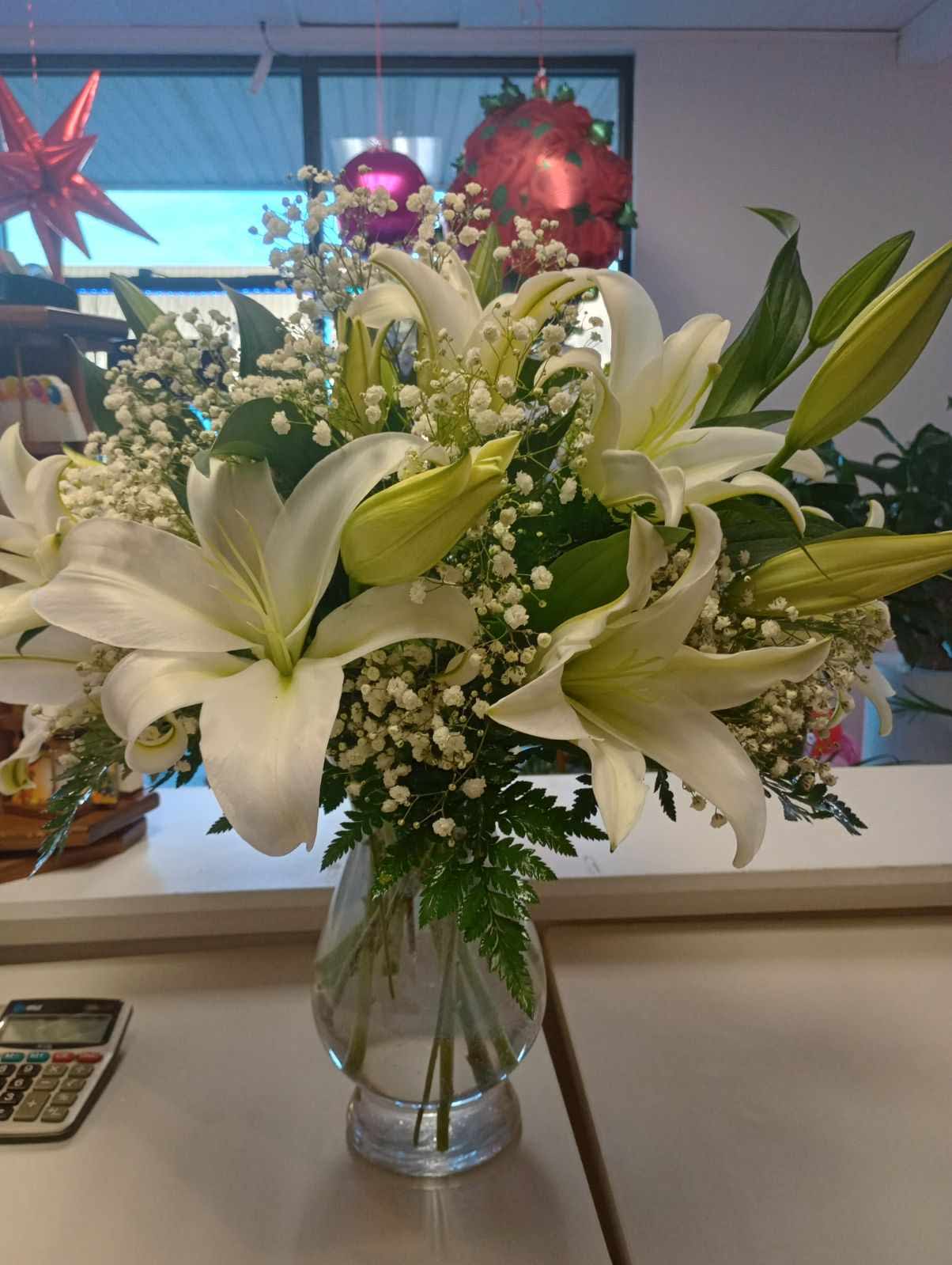 White Lillies w/ Babies Breath - A beautiful small clear vase full of white lillies and babies breath.  Add your favorite box of chocolates, teddy bear, or balloon to make the perfect Valentine's Day gift.