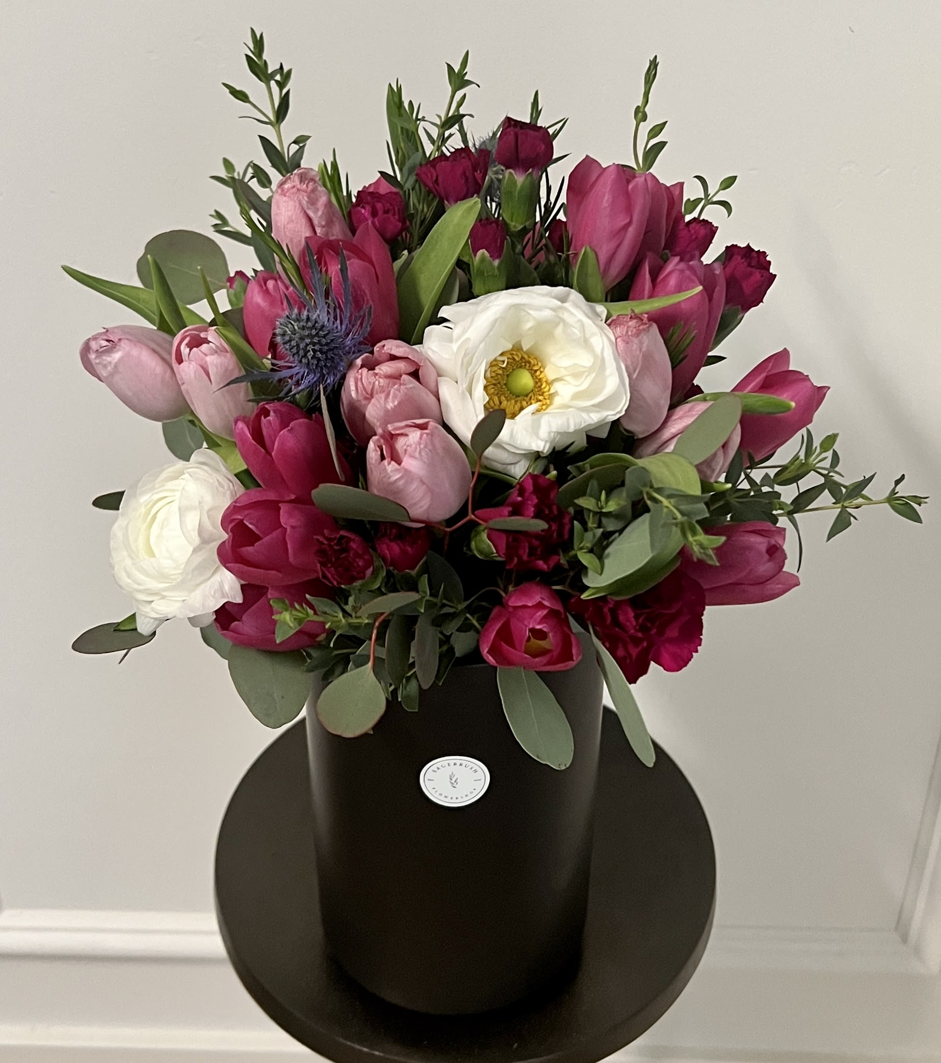 Pink  - mix of tulips, carnations, ranunculus, wax flower and greenery.   If tulips are out of seasons florist will replace with like color flowers. 