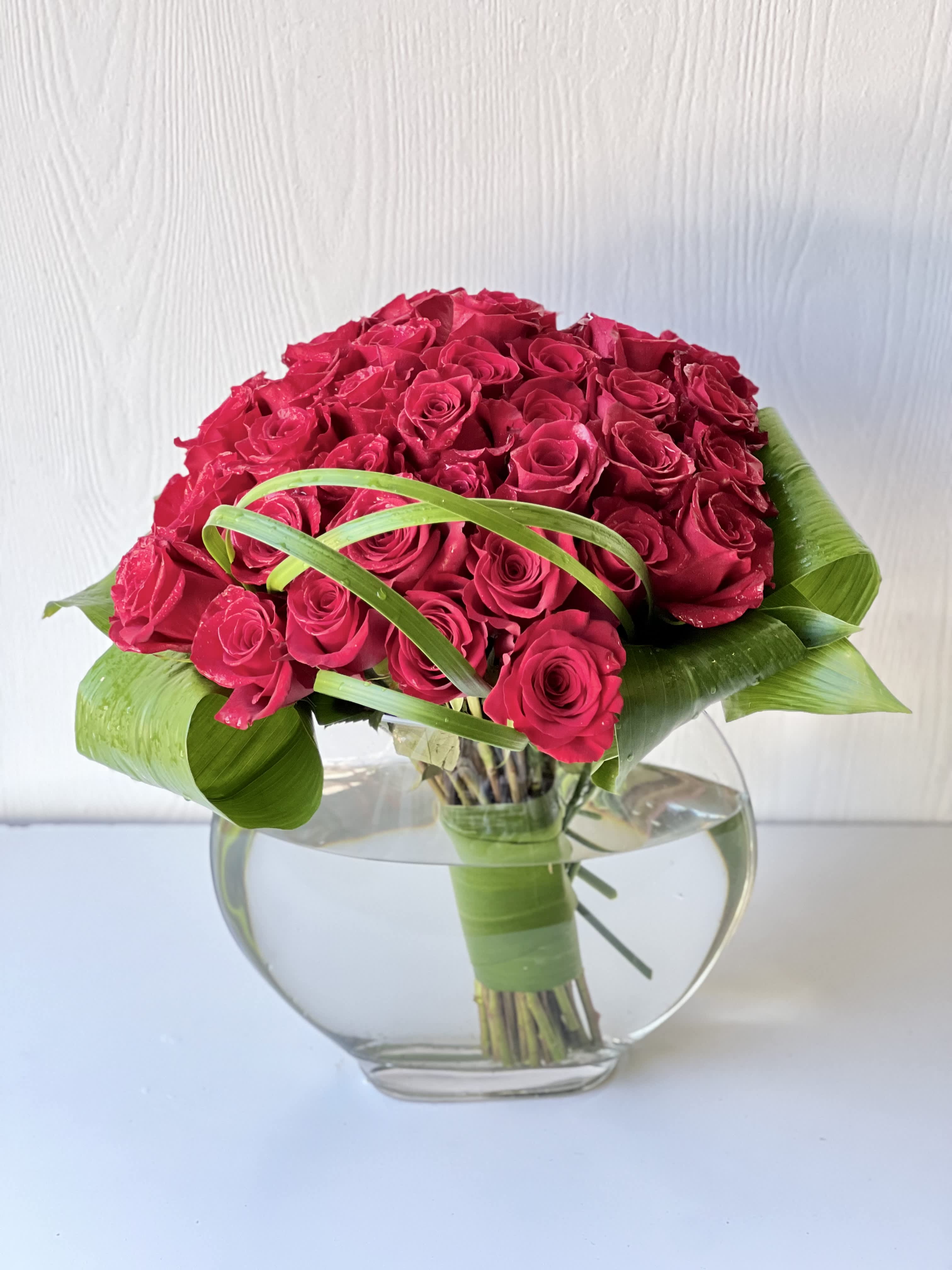  EC95 - My True love Bouquet  - This breathtaking bouquet features 3 dozen red roses arranged in a sleek clear glass cylinder. The roses themselves provide a stunning pop of color, while the glittery butterflies add a touch of magic and whimsy. This gorgeous gift is perfect for a range of special occasions, such as weddings, birthdays and anniversaries. The bouquet is grand and celebratory, making it a fantastic way to express love, gratitude or congratulations. 