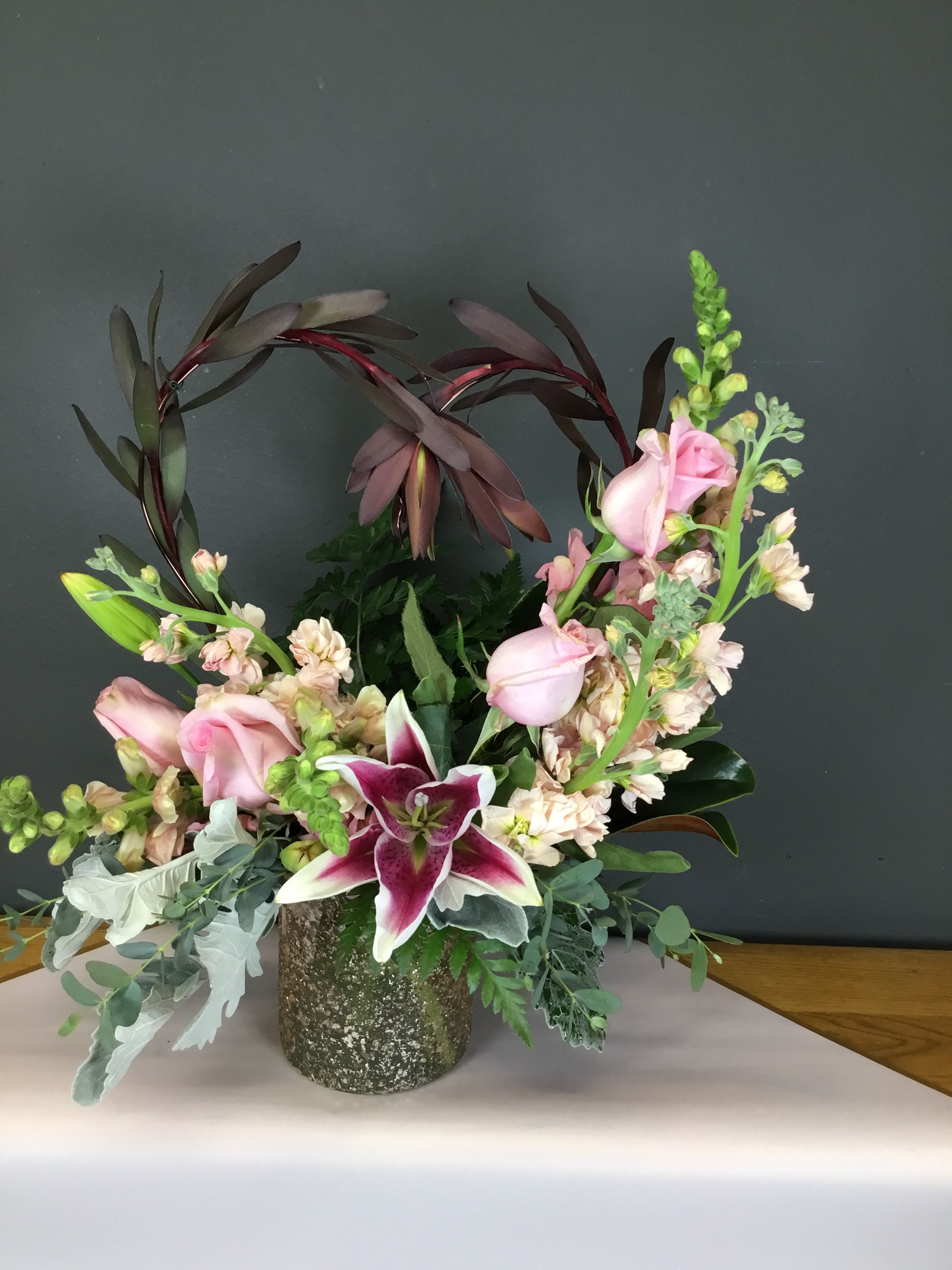 Champagne Dreams - Pretty Champagne colored vase with Sunset Safari, Starfighter Lily, Peach Roses with Peachy/Pink Snapdragons and Stock.