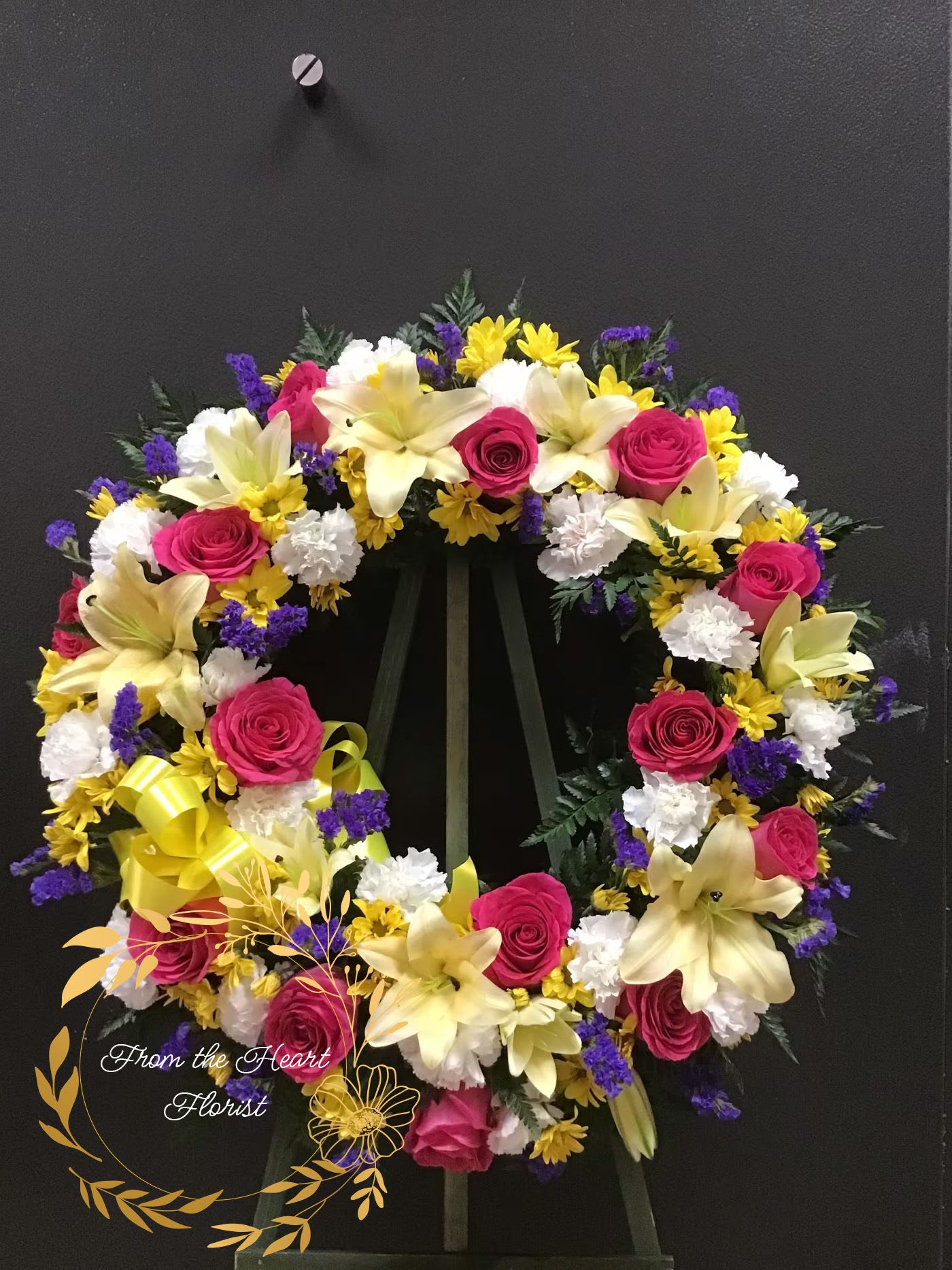 Yellow Pink Blue and White Wreath (FW32) - This beautiful wreath made with hot pink roses, yellow liliez white carnations and blue static 