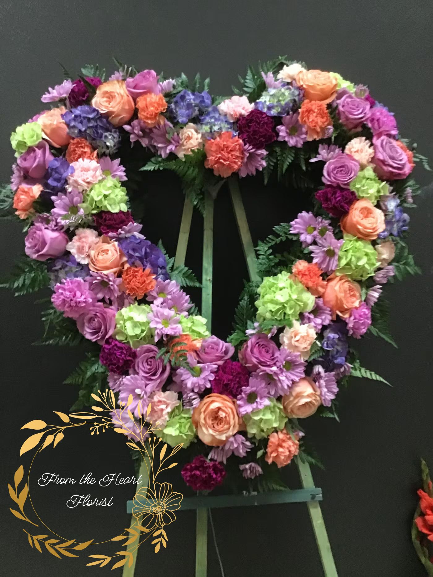 Peach and purple open heart (FH23) - This open heart made with green hydrangea, purple roses, carnations , daosy. and peach roses. amd orange carnations .
