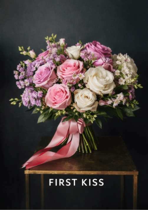 First Kiss: Hand-tied Bouquet - FIRST KISS  Soft, airy, and romantic. A bloom-forward hand-tied bouquet featuring Pink Expression and Queen’s Crown roses, lightly accented with delicate waxflower for movement and texture.  PART OF OUR LOVE IN EVERY ERA — HAND-TIED BOUQUET COLLECTION Featuring First Kiss, All In, and After Dark  This Valentine’s collection is intentionally bloom-forward, designed around a tightly curated selection of premium rose varieties. To honor the integrity of each design, we are limiting our Valentine’s stock to these featured blooms, allowing the flowers themselves to take center stage. Our hand-tied bouquets are lush, expressive, and light on traditional fillers; instead, we use delicate waxflower as our primary accent to maintain a refined, floral-forward composition.  Images shown are renderings and are representative of overall size, style, and color palette.