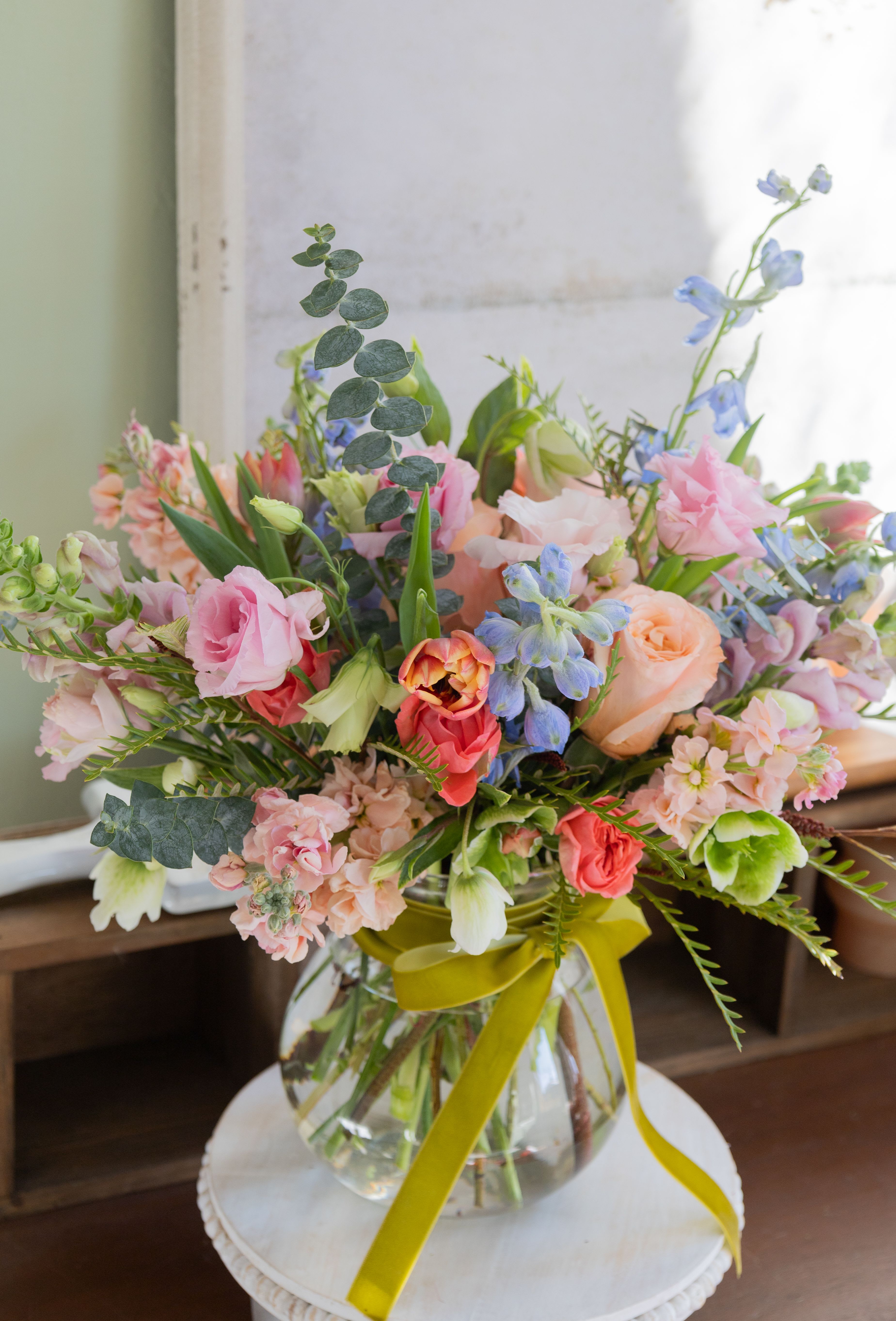 Hippie Girl - For those who like something a different! Peachy roses, varigiated tulips, eucalyptus (for fragrance too!) and a touch of blue.  arranged in a clear glass vase and tied with a velvet ribbon