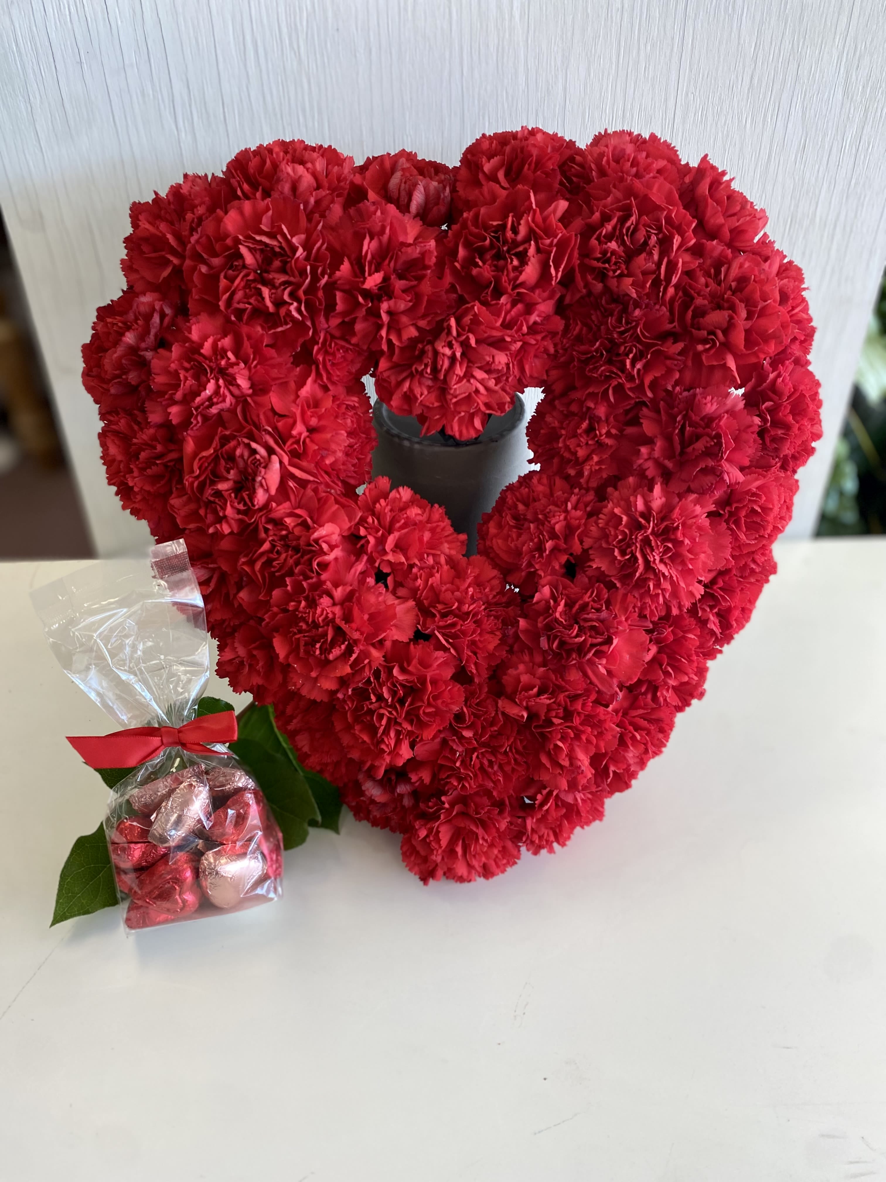 From the Heart - A beautiful and unique arrangement of long lasting carnations in the shape of a heart, made even more special with the addition of Chocolate hearts. Heart is approx 16"x16",