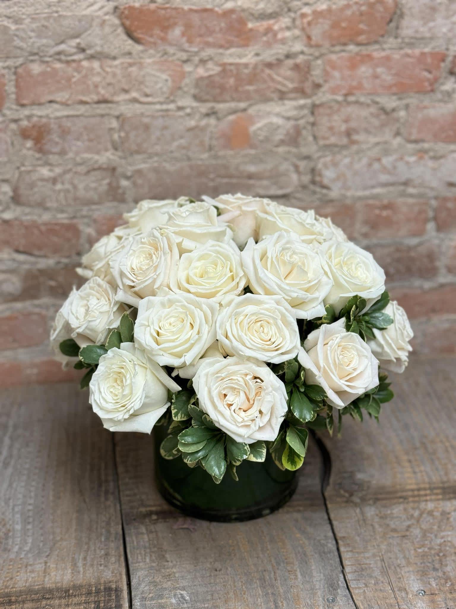 Two Dozen White Roses "In a bush" - Two dozen white roses in a low, clear vase with greenery.