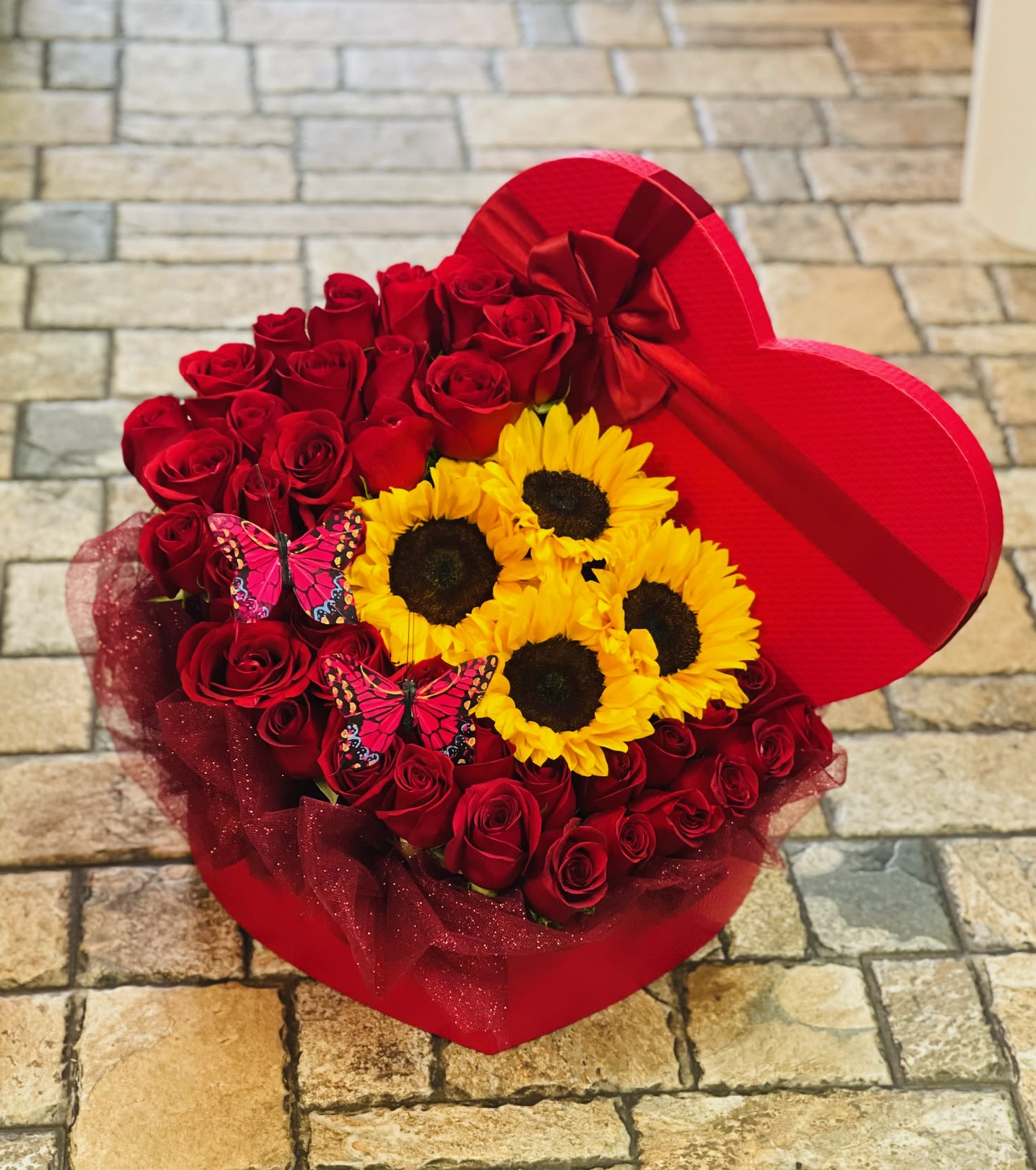 Love and Sunshine in a Box - This beautiful gift box is filled with high quality red roses, vibrant sunflowers, and lush accents of greenery. Surprise your loved one today with this timeless combination. 