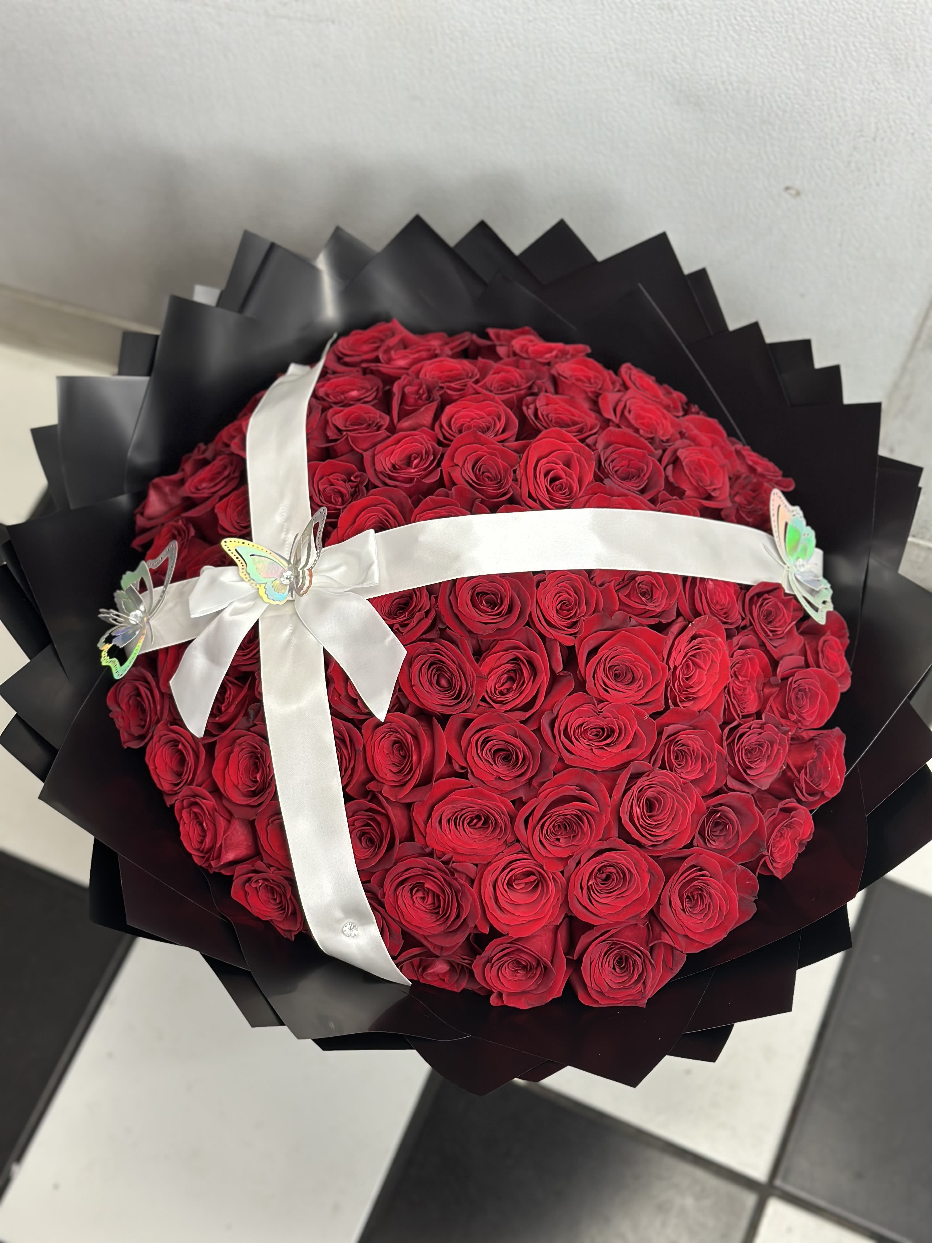 All Rose Bouquet (75ct.) - 75 roses arranged into a round bouquet with the color paper of your choosing and color of rose of your choosing. Accessories included.