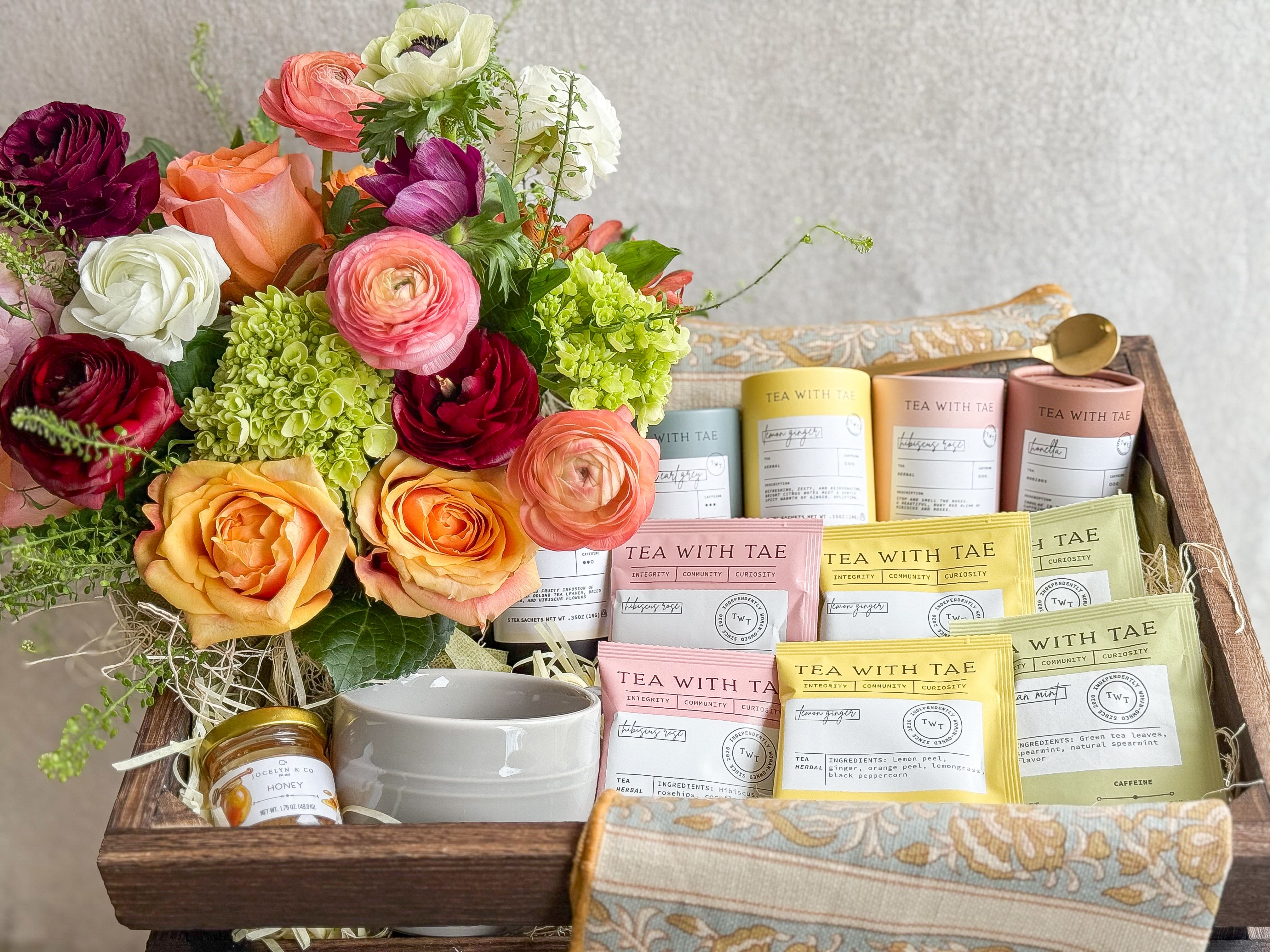 Flowers &amp; Tea Gift Basket  - Gift in good taste with this elegant assortment of treats. A seasonal lush floral arrangement, Tea Mug, Honey, Golden Spoon,   floral pattern tea towel,  and an assortment of teas.   All designed in a large wooden crate, includes handwritten card.   You deserve the best. If an item is unavailable, we’ll sub in products of equal or greater value.