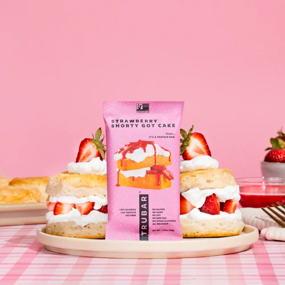 Strawberry Shorty Got Cake - The TRUBAR Strawberry Shorty Got Cake strawberry cake protein bar is a sumptuous, guilt-free treat bar.  For those who:  Crave the rich, indulgent combination of fresh strawberries and fluffy cake. Desire a delightful snack that provides genuine nourishment anytime, anywhere. Get a thrill from the sweet aroma of cake fresh out of the oven. 190 calories per bar 12g of plant protein 12 bars per box  Vegan No Gluten, No Dairy, No Soy, No Sugar Alcohols, No Seed Oils GLP-1 Friendly: Full of protein and fiber, perfect for your GLP-1 needs.
