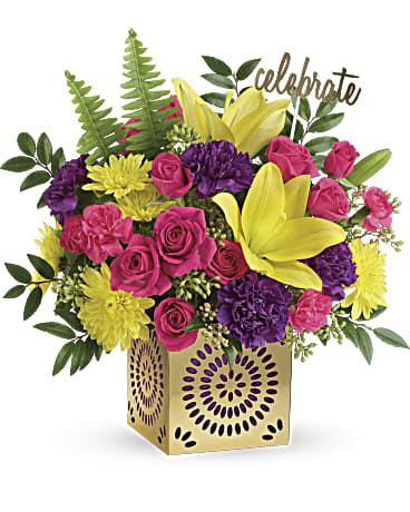 Colorful Celebration Bouquet - Color their day happy with this bright surprise! Artfully arranged with a Celebrate pick in a gleaming golden cube with delicate punched details, this sunny bouquet of yellow lilies and hot pink roses celebrates them in style. This joyful bouquet includes hot pink spray roses, yellow asiatic lilies, purple carnations, hot pink miniature carnations, yellow cushion spray chrysanthemums, huckleberry, seeded eucalyptus, and sword fern. Delivered in a Celebrate in Style cube. Approximately 14" W x 14 1/4" H