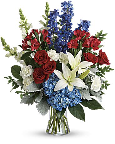 Colorful Tribute Bouquet DX - Perfectly patriotic with its red, white and blue blooms, this bold bouquet of hydrangea, lilies and roses is a versatile tribute on any occasion. This bouquet features blue hydrangea, red roses, white asiatic lilies, red alstroemeria, white carnations, blue delphinium, white snapdragons, huckleberry, dusty miller, aralia leaf and lemon leaf. Delivered in a gathering vase. Approximately 22" W x 26" H