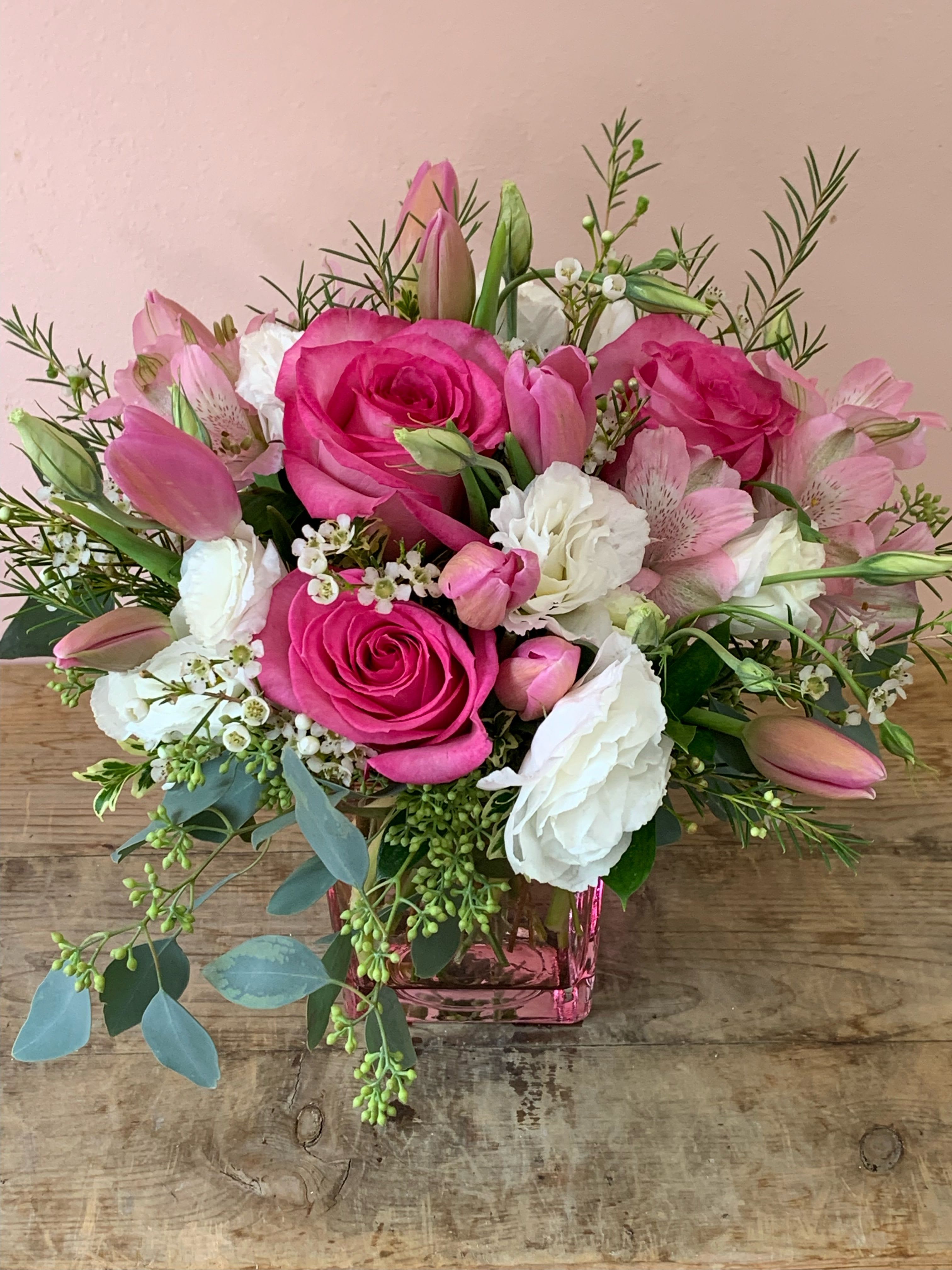 Lovely In Pink Flowers by Fillmore Florist in San Francisco - Ready for San Francisco flower delivery is Lovely in Pink Flowers. Stun your better half with this delightful, chic, pink and white flower arrangement. Tastefully arranged in a cube pink glass vase sits, pink Roses, white Lisianthus, pink Tulips, and pink Alstroemerias. There’s no other better way to let your person know you are thinking of them with Fillmore Florist flower delivery in San Francisco. As a top rated and regarded florists in San Francisco we feel the responsibility to deliver greatness with flowers every time. This flower arrangement is available for same day delivery! (before cut off times)   Dimensions: 12 H x 10 W
