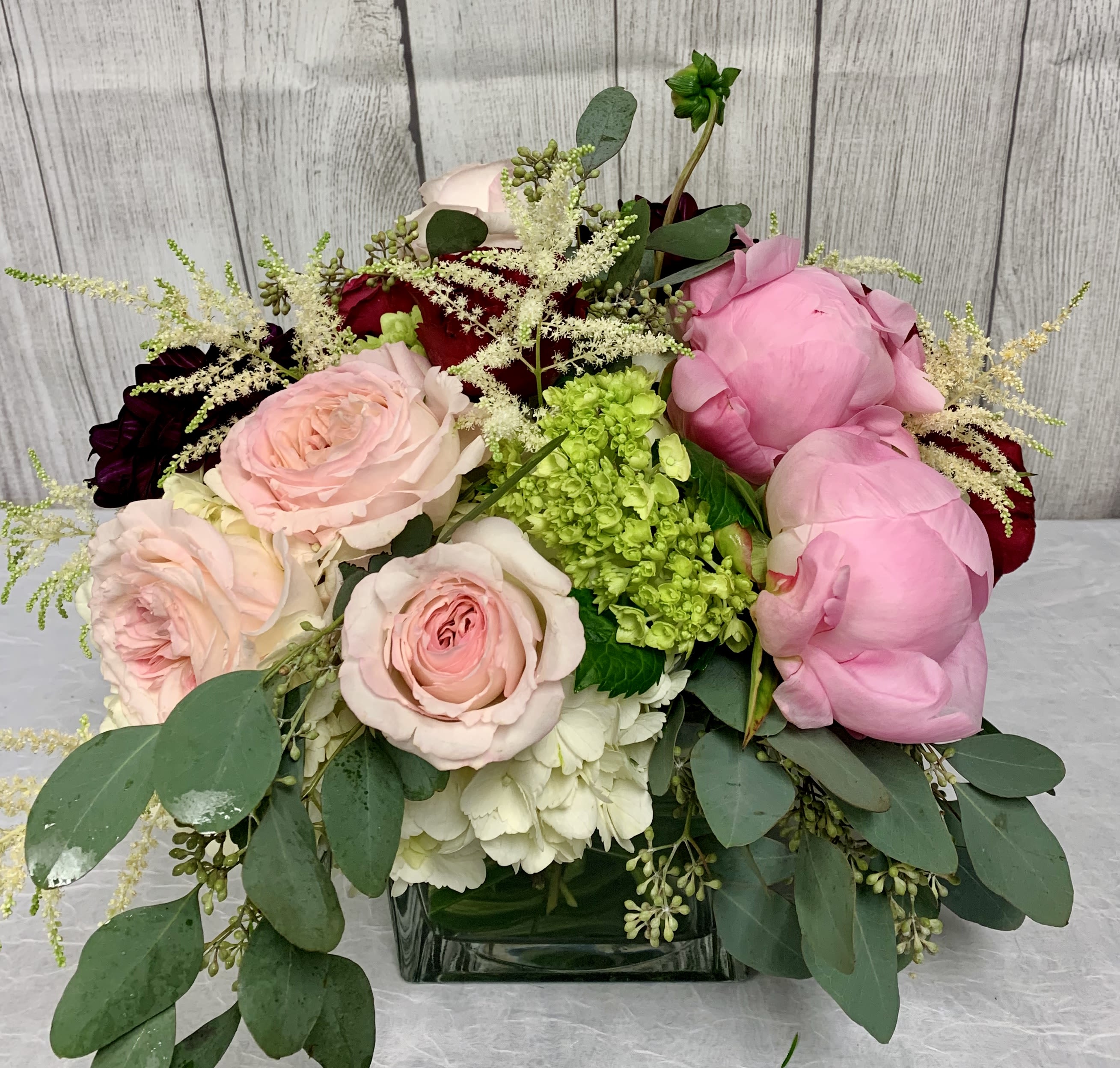 V115 - A low compact arrangment of high end flowers in pinks, white and green such as roses, hydrangeas and other high end blooms. 